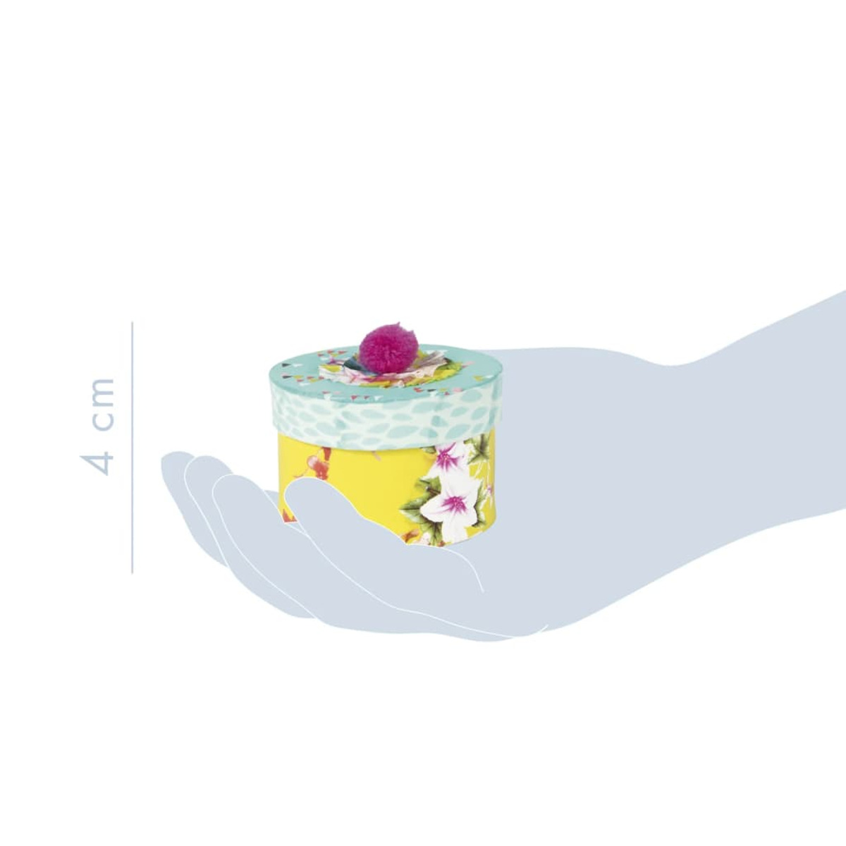 Eine Hand, die eine kleine, runde, gelbe Schachtel mit Blumen- und Pompon-Dekorationen hält.
