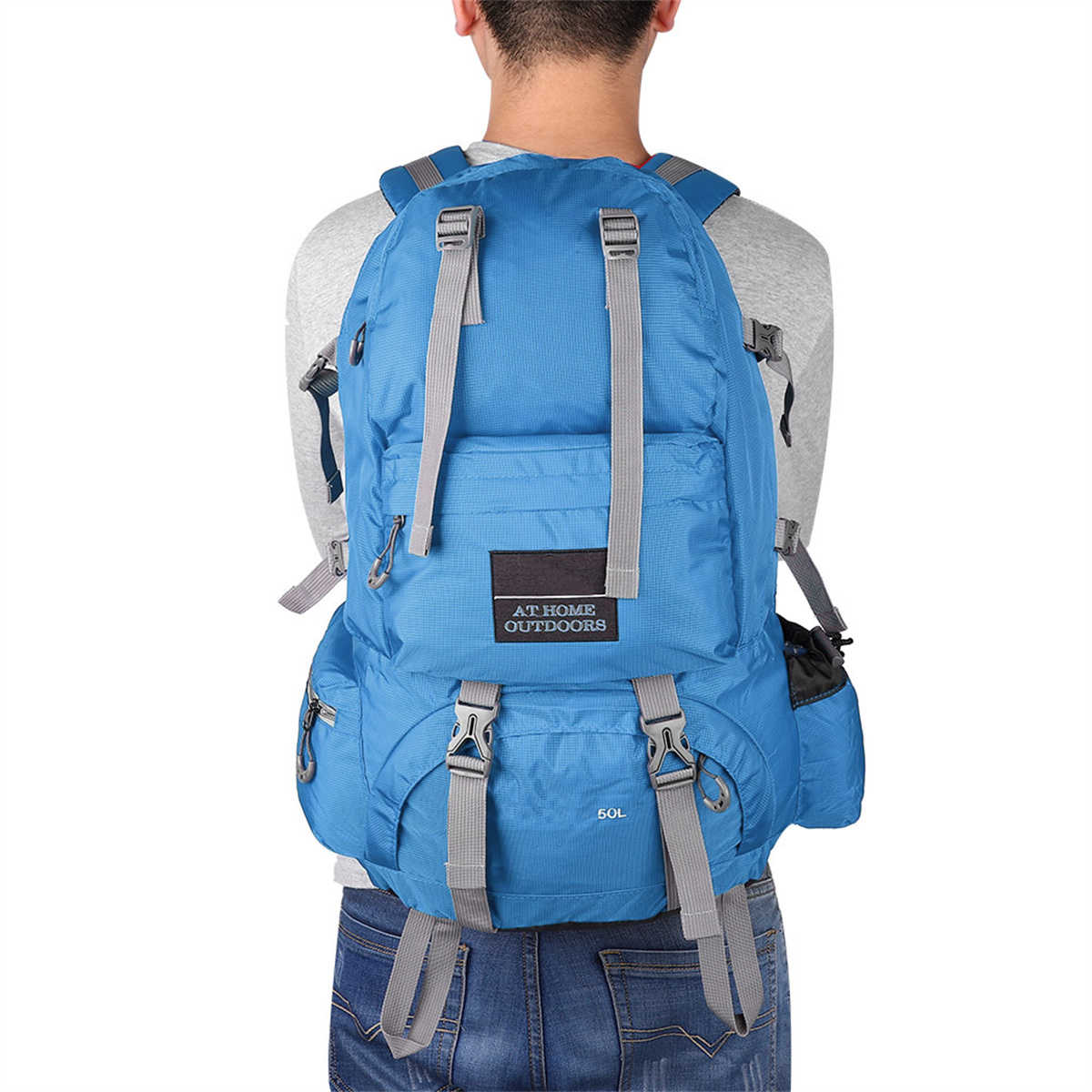 Person mit blauem Rucksack mit der Aufschrift 'AT HOME OUTDOORS' und '50L'.