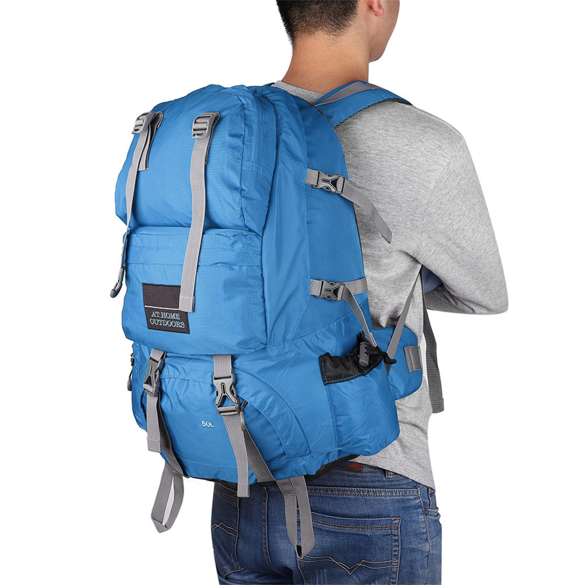 Blauer Rucksack auf dem Rücken eines Mannes. Graue Träger, graues Hemd und Jeans.