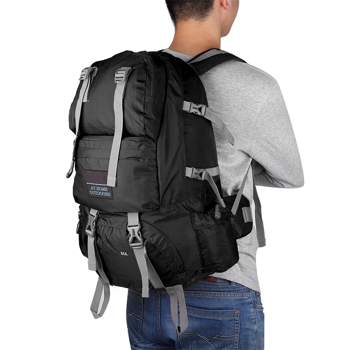 Ein Mann, der einen schwarzen Rucksack mit grauen Trägern trägt, von hinten gesehen.