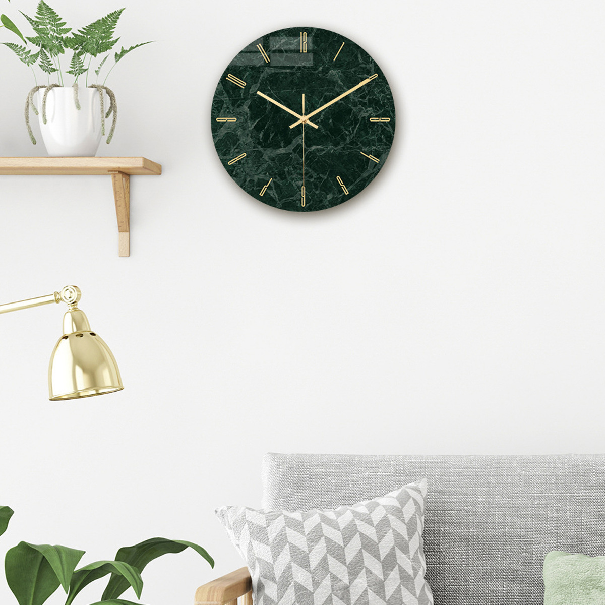 Grüne, marmorähnliche Wanduhr mit goldenen Zeigern und Zahlen, an einer weißen Wand.