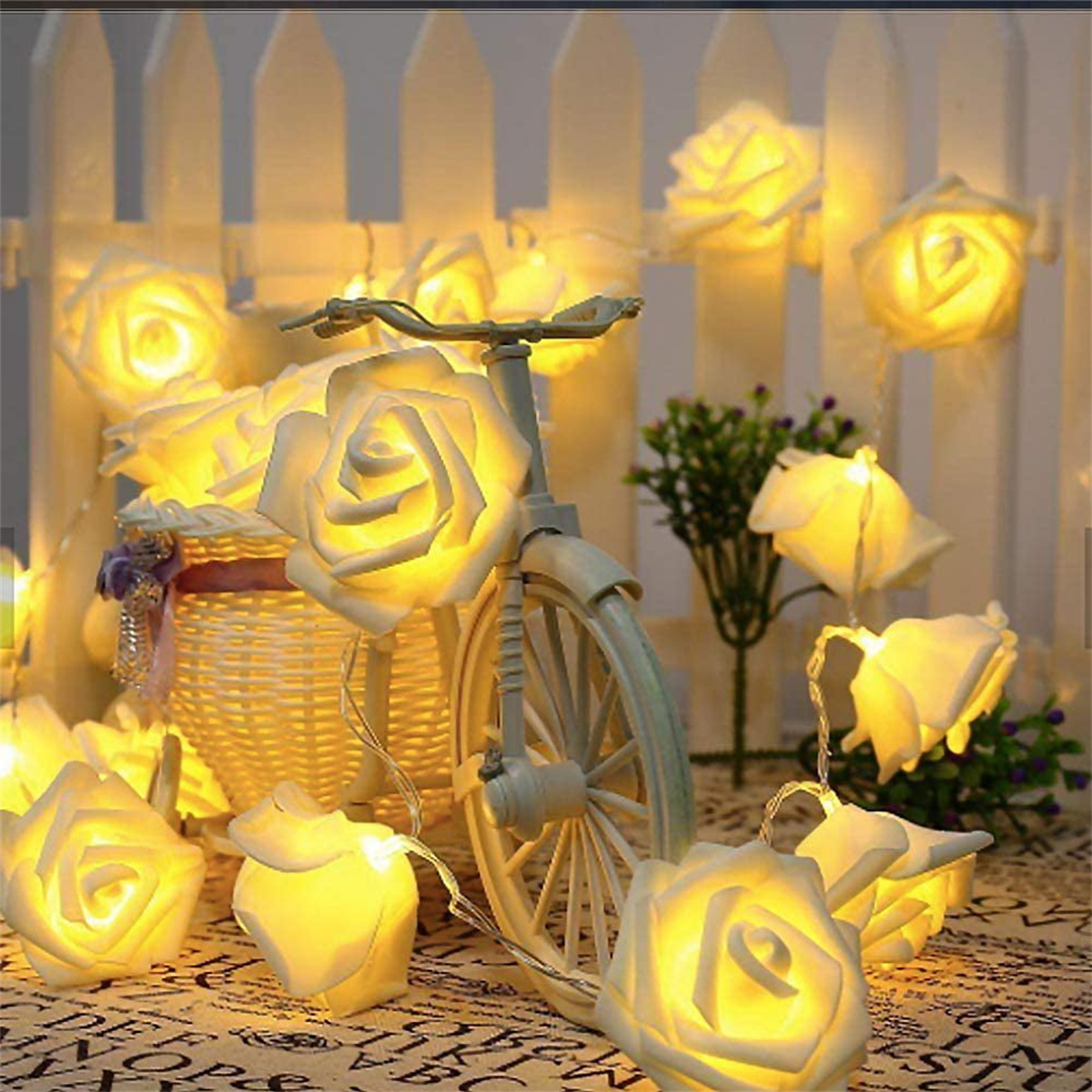 Beleuchtete rosenförmige Lichter. Ein Fahrrad steht im Vordergrund. Dunkler Hintergrund.