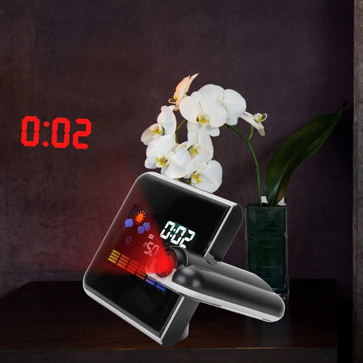 Eine schwarze Uhr, die Zeit und Wetter projiziert. Weiße Blumen stehen rechts in einer Vase.