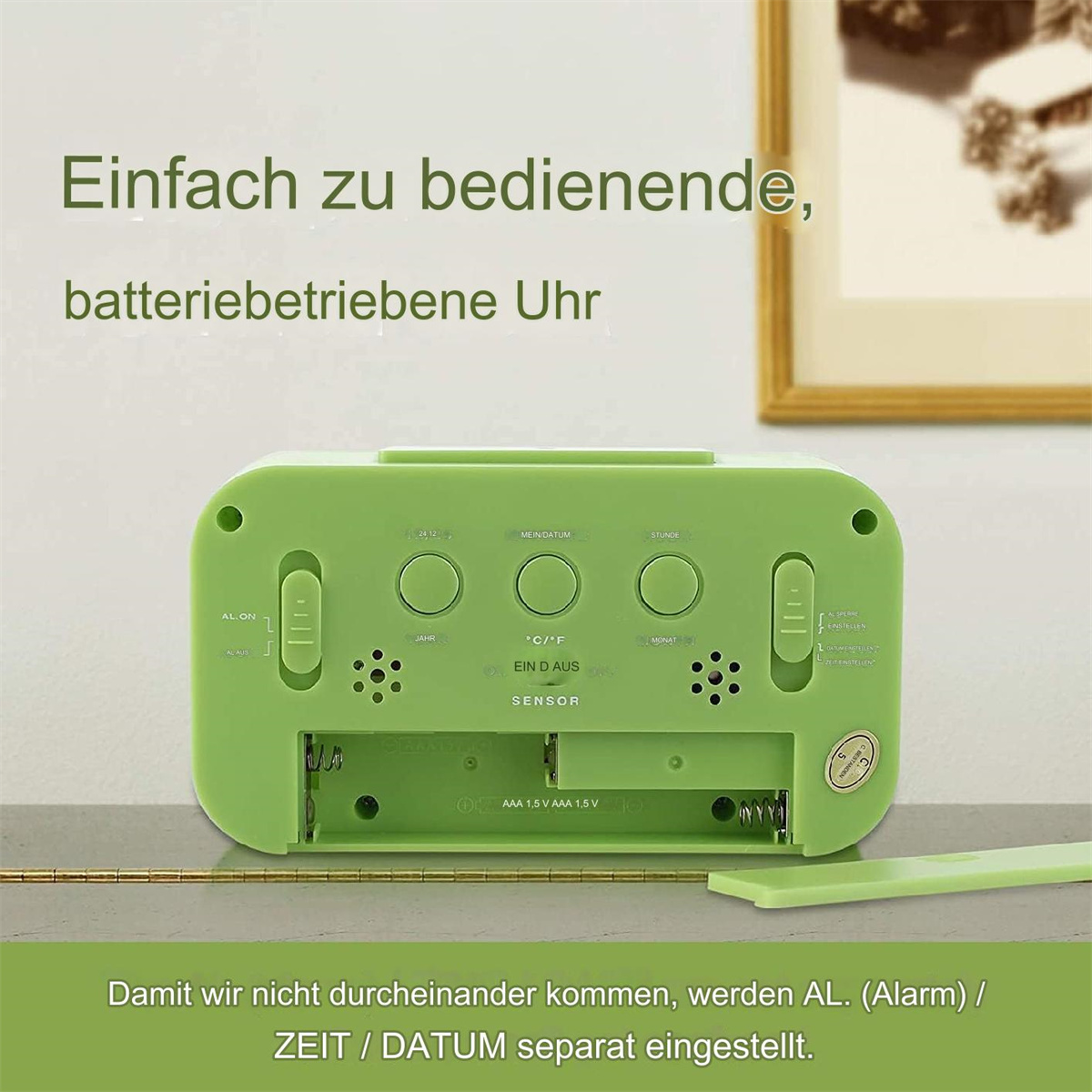 Grüner Wecker mit Knöpfen, Batteriefach offen. Weißer Hintergrund.