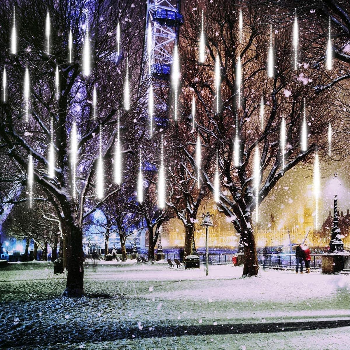 Verschneite Winterszene mit Bäumen und fallenden Lichtern. Die Bäume sind kahl. Menschen gehen im Hintergrund.