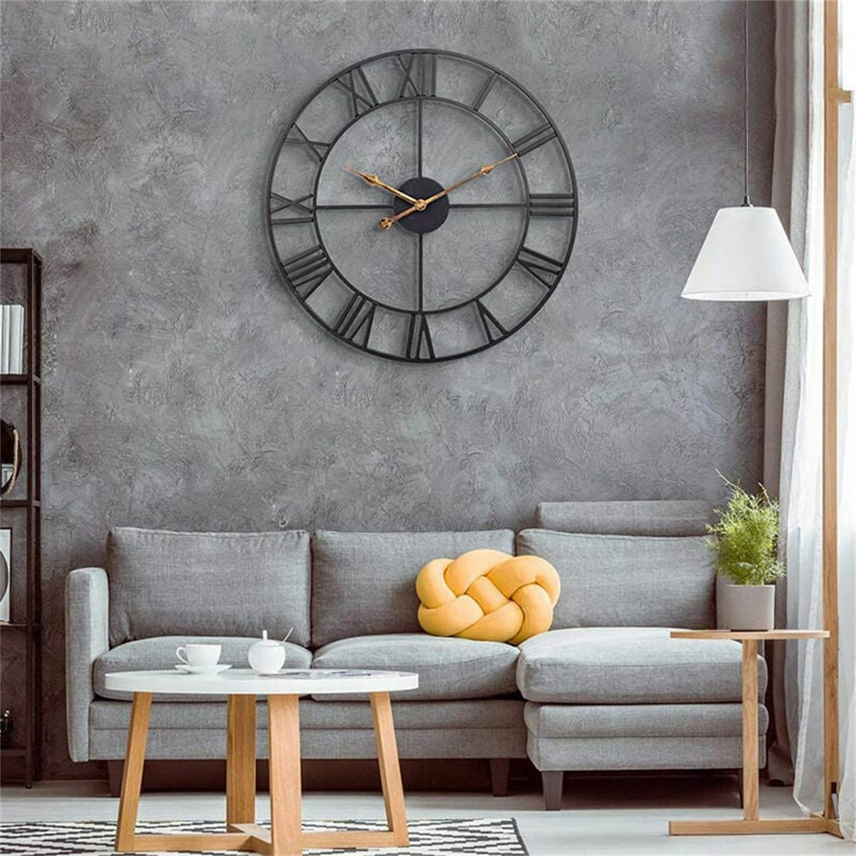 Wohnzimmer mit grauem Sofa, schwarzer Uhr, Couchtisch und weißer Lampe.