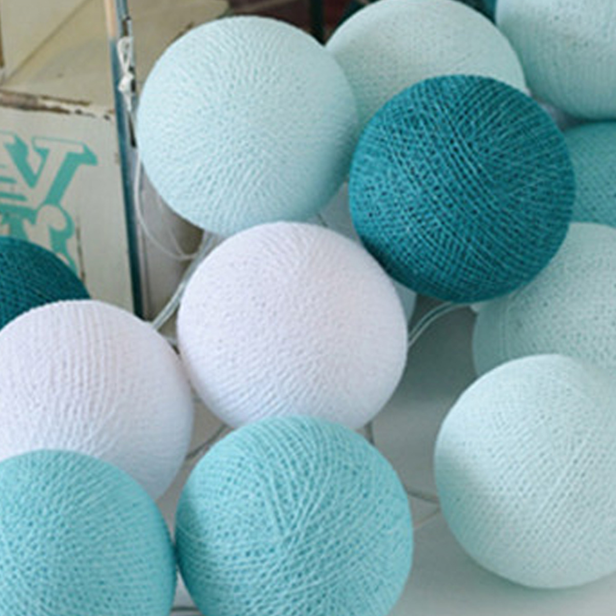 Nahaufnahme von mehreren Watteball-Lichtern in Weiß, Teal und Hellblau.