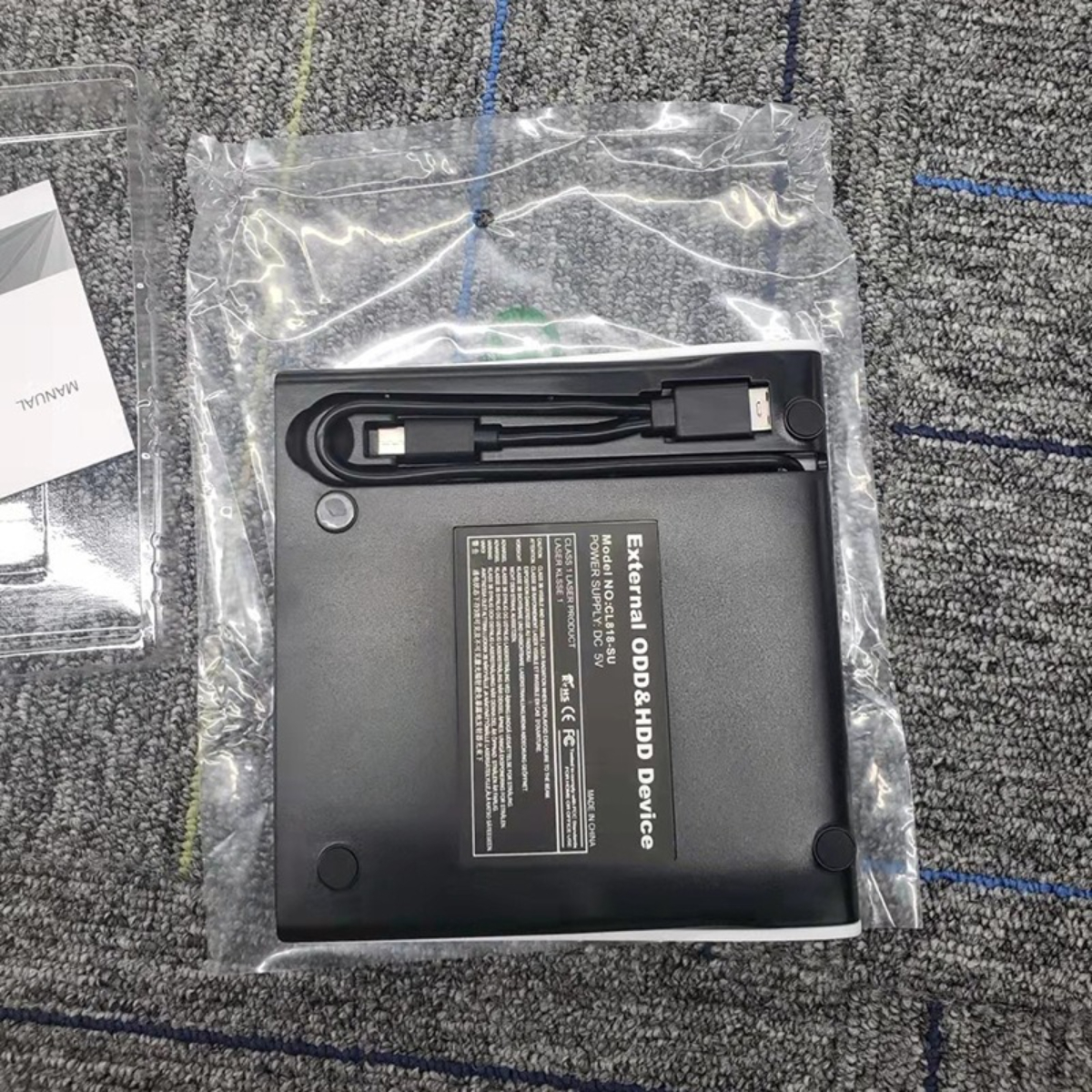 Schwarzes externes ODD & HDD-Gerät in Kunststoff. Weißes Handbuch.