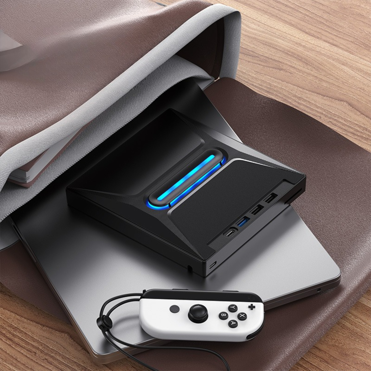 Schwarzes Gaming-Gerät in einer Tasche, Controller daneben. Blaues Licht am Gerät.