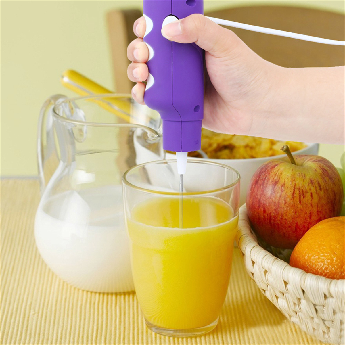 Eine Hand hält einen lila Stabmixer und mixt Saft in einem Glas.