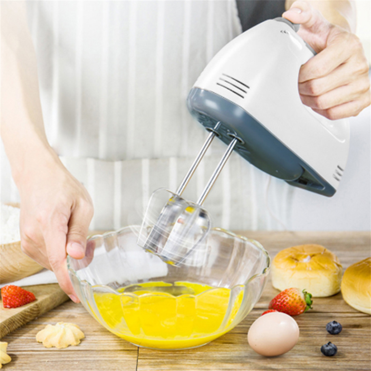 Person mit weißem Handmixer, der Eier in einer Schüssel mit Zutaten verrührt.