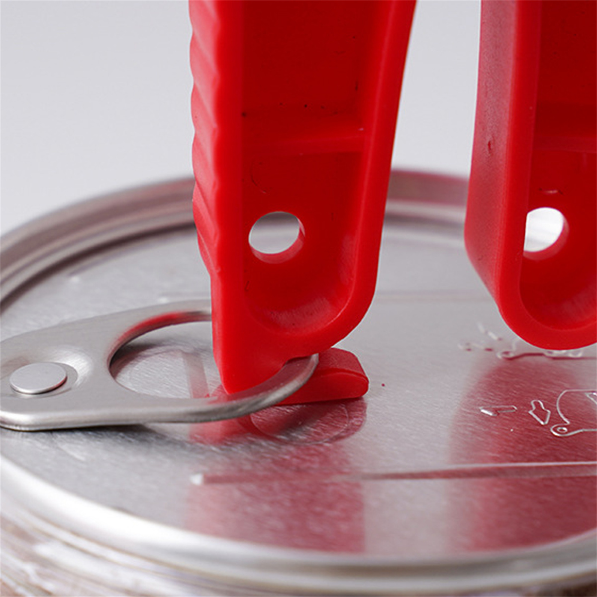 Ein roter Dosenöffner in Aktion. Der Öffner ist auf einer Dose positioniert, bereit, den Deckel zu entfernen.