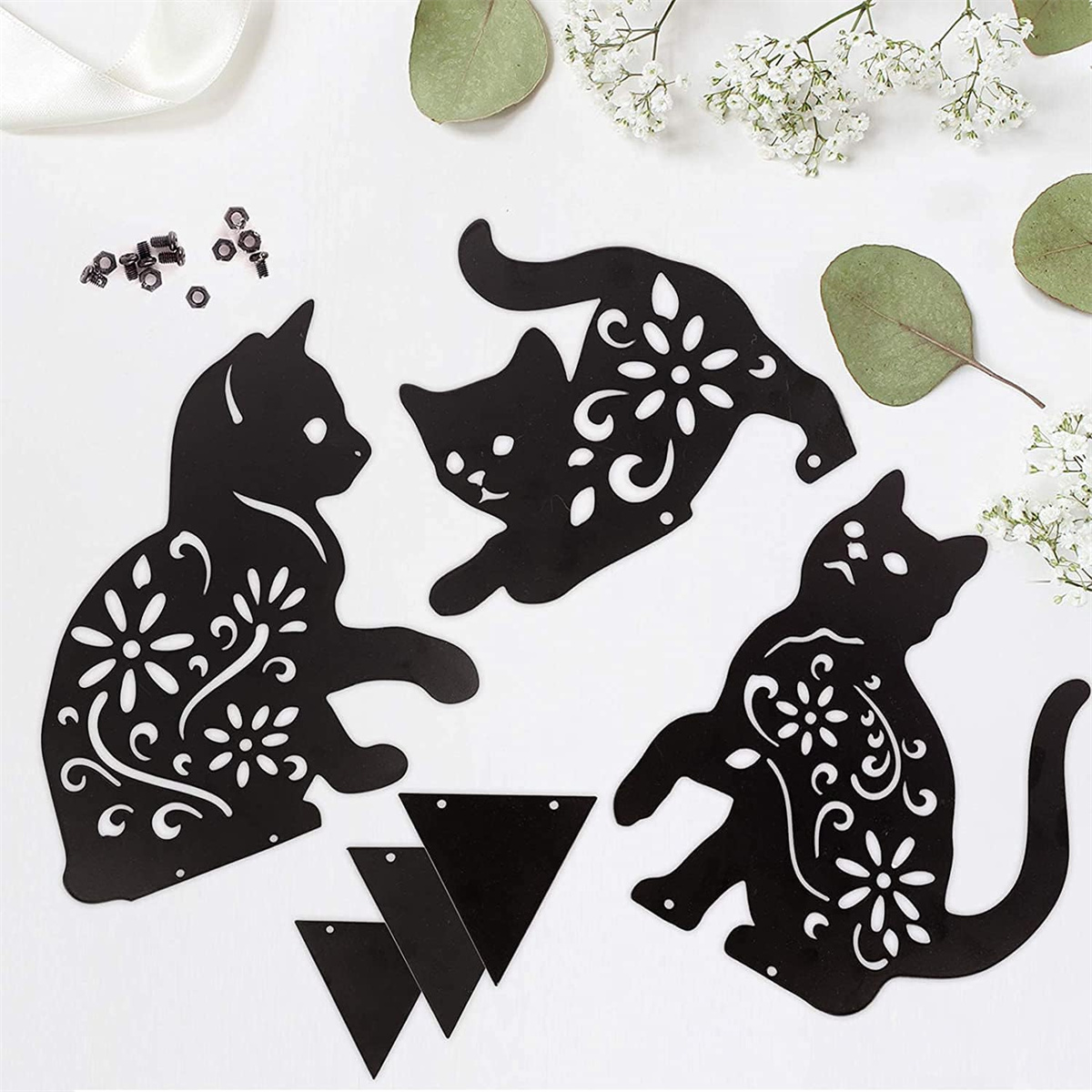 Schwarze Katzenausschnitte mit floralen Mustern. Weißer Hintergrund. Dreiecke und Blumenakzente sind vorhanden.