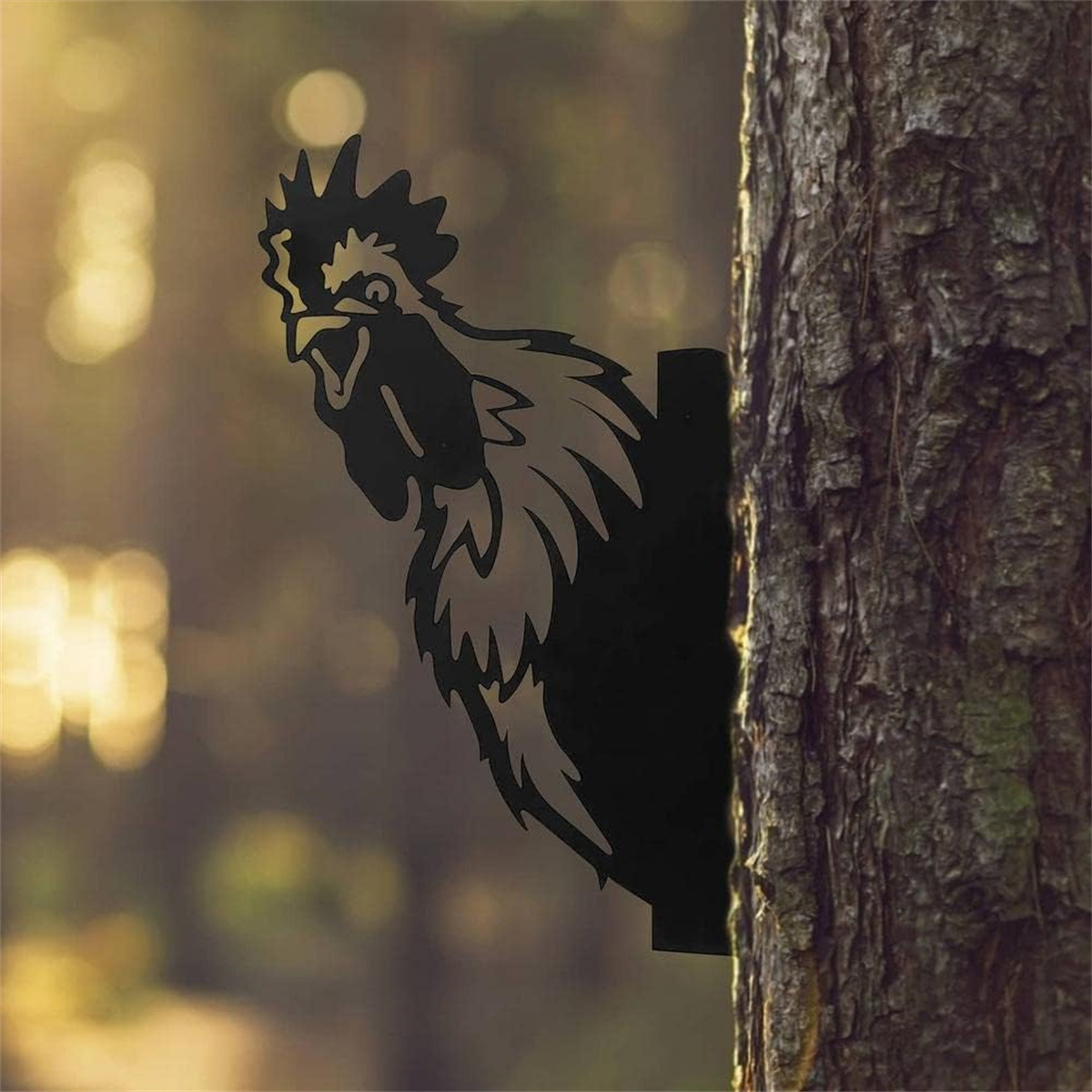 Eine metallene Hahnsilhouette an einem Baum befestigt. Der Hintergrund ist ein verschwommener Wald.