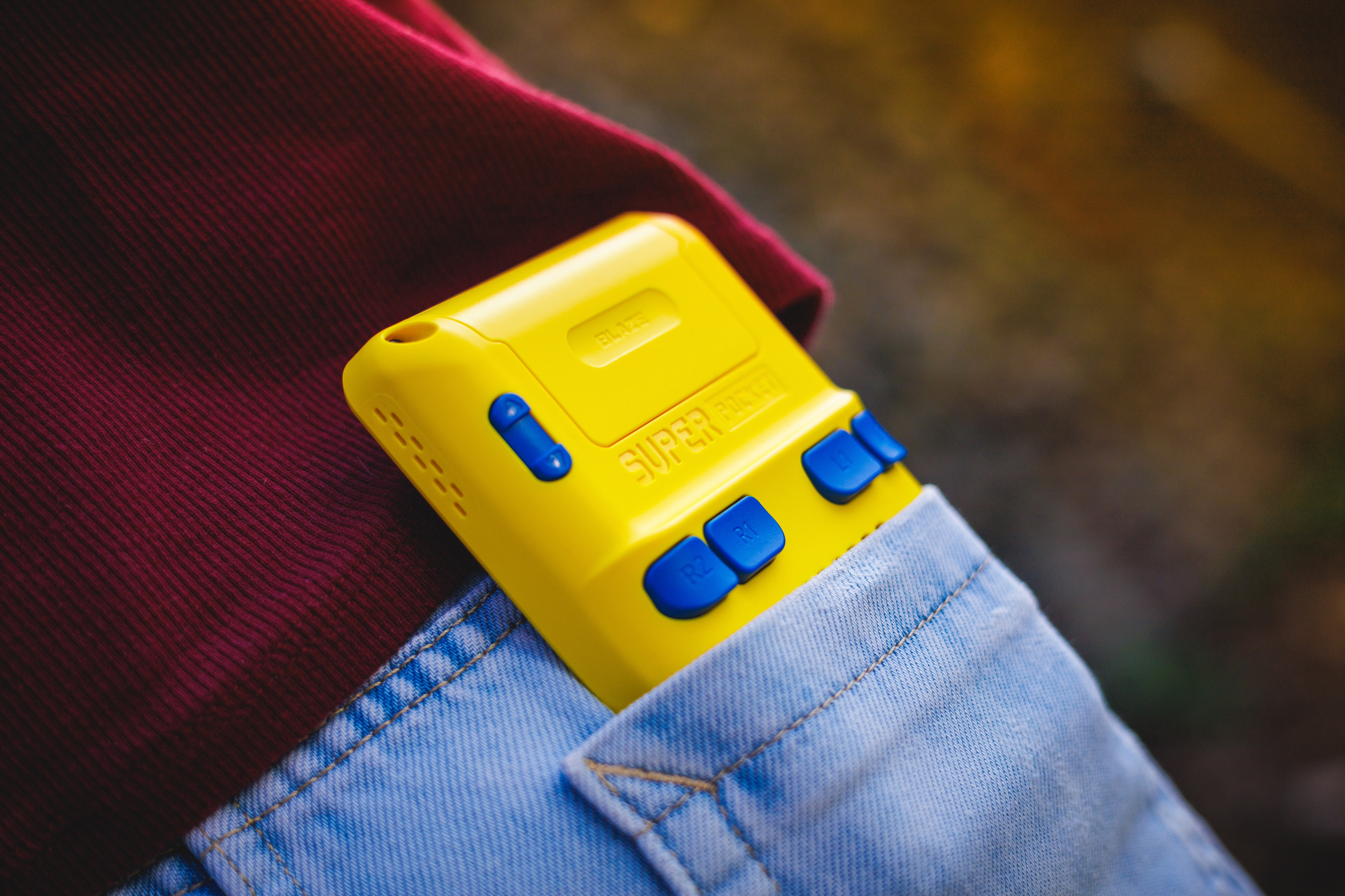 Żółta konsola do gier Super Pocket w niebieskiej kieszeni dżinsowej.