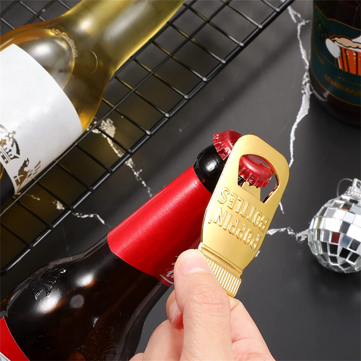 Ein goldener Flaschenöffner auf einer roten Flasche mit schwarzem Verschluss. Er ist mit 'POPPTN BOTTLES' beschriftet.