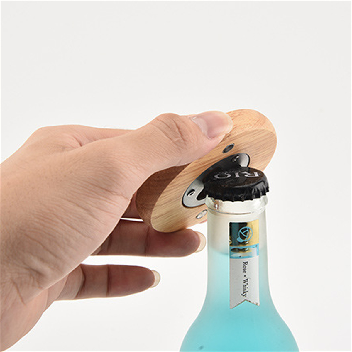 Hand öffnet Flasche mit blauem Getränk mit Holz-Flaschenöffner.