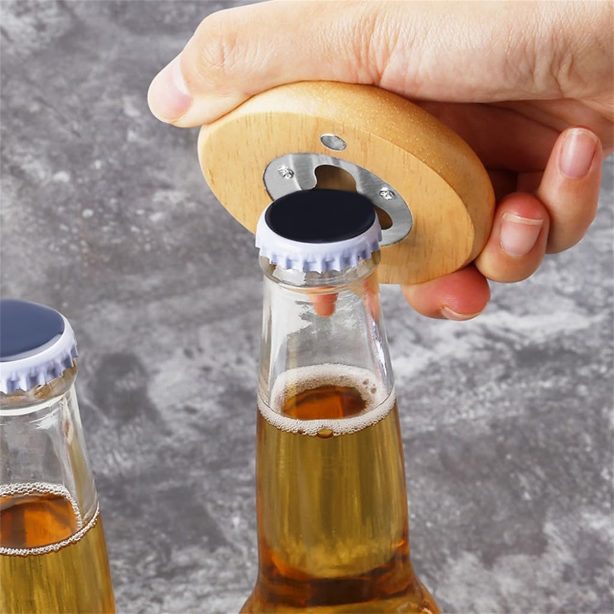 Eine Person öffnet eine Bierflasche mit einem hölzernen Flaschenöffner. Das Bier ist goldfarben.
