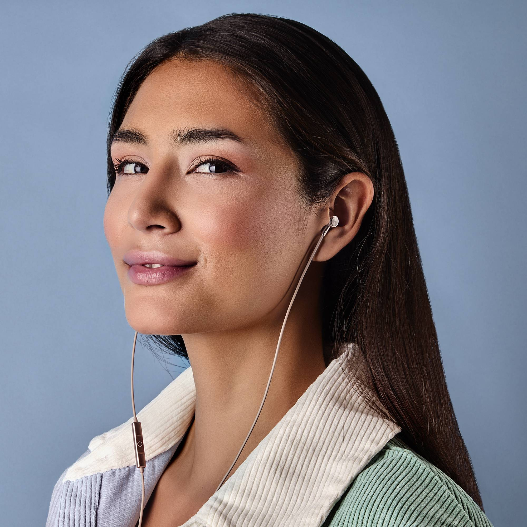 Una donna con lunghi capelli scuri indossa un auricolare nell'orecchio sinistro, sorridendo alla fotocamera.