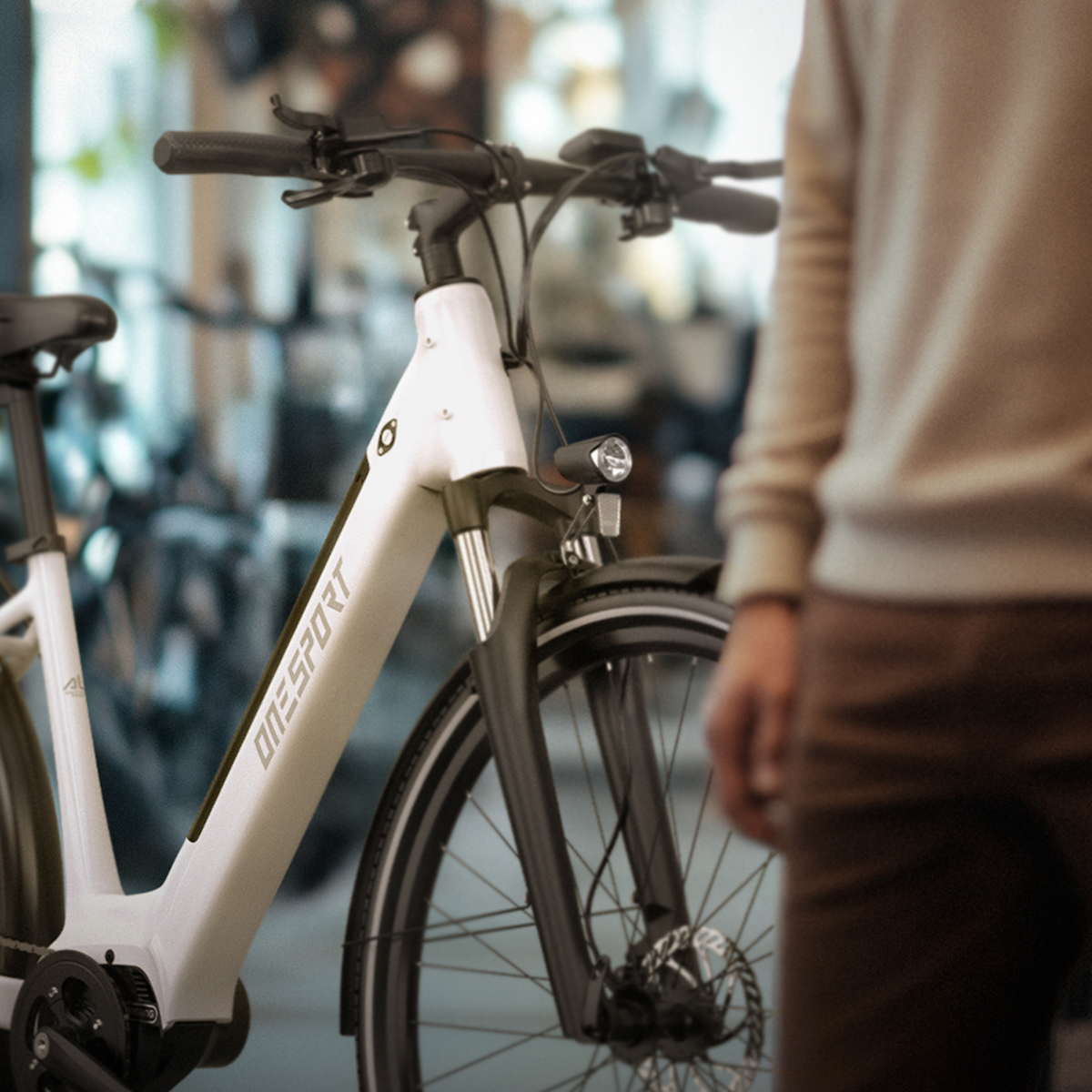 Bicicletta elettrica bianca e nera. Una persona è nello sfondo sfocato.