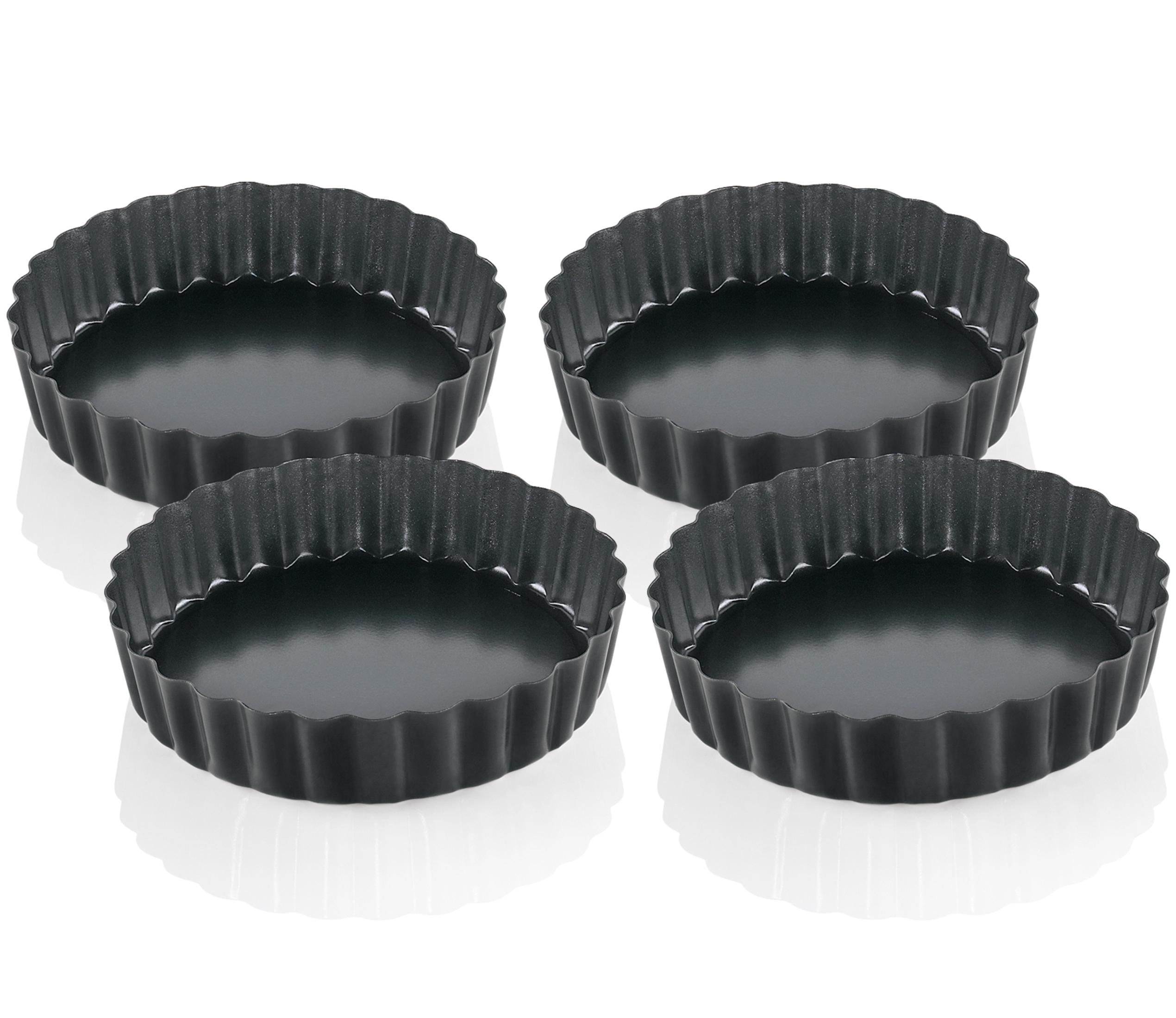 Vier schwarze Tarteformen mit geriffelten Rändern, nebeneinander angeordnet.