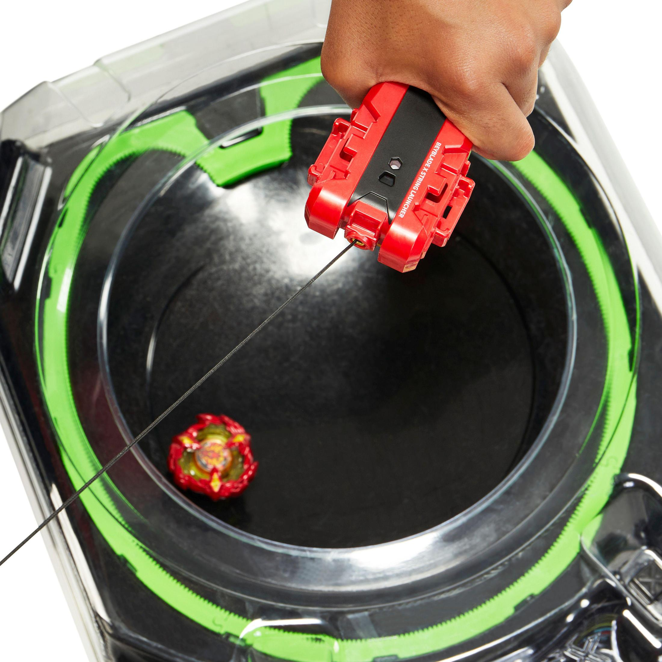 Beyblade arena met twee ronddraaiende tops en een hand die een lanceerder vasthoudt.