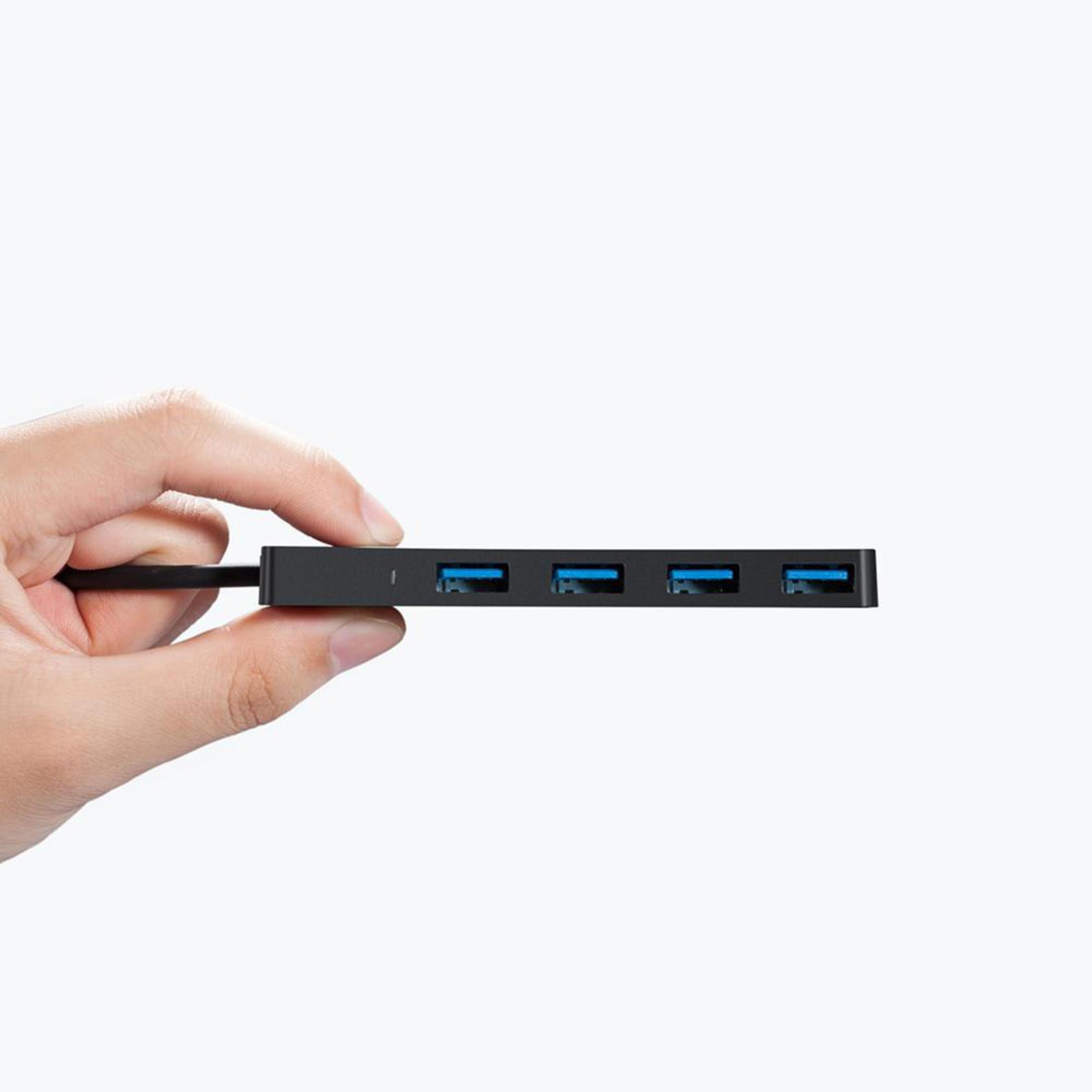 Hub USB nero con quattro porte. Una mano tiene l'hub. Sfondo bianco e illuminazione neutra.