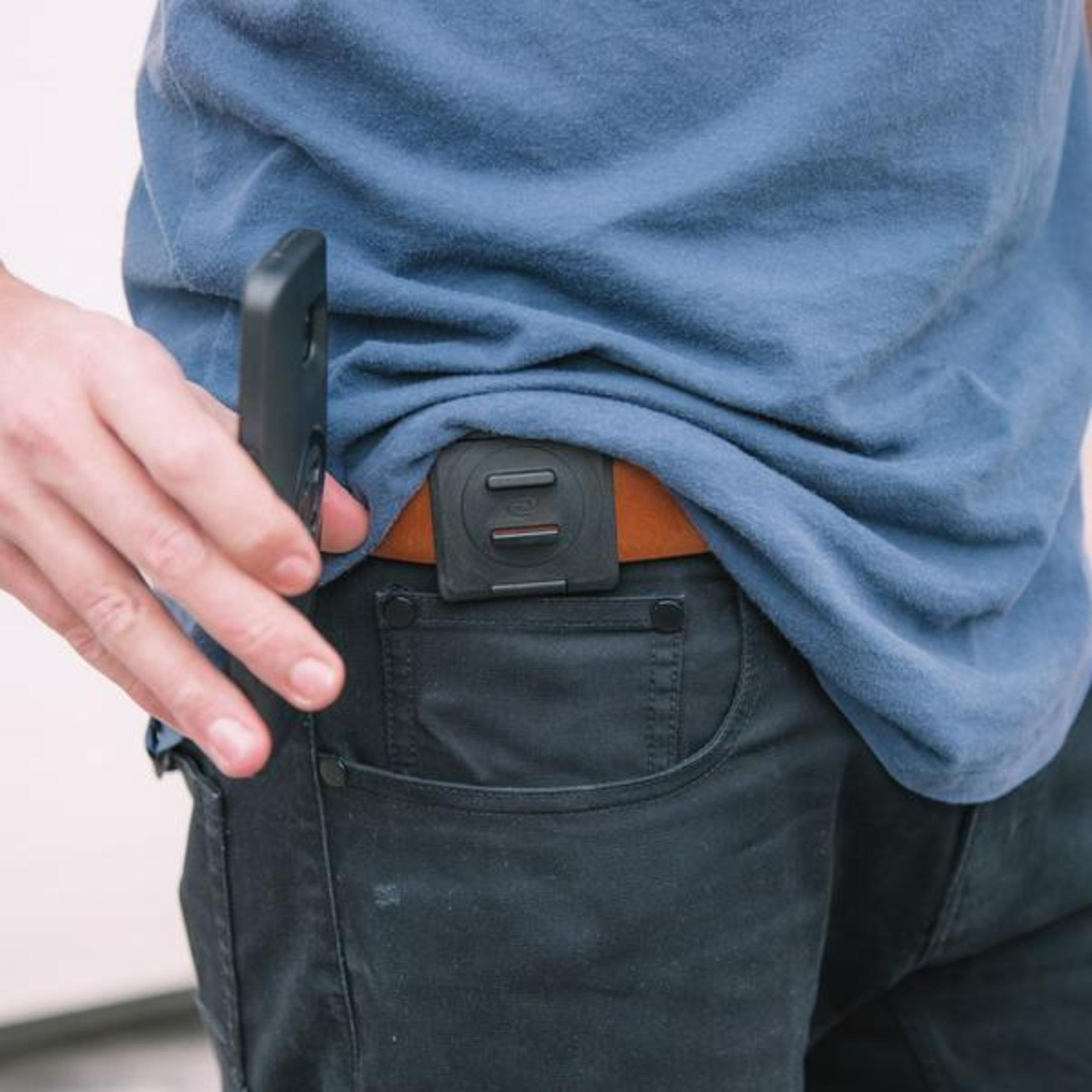 Person trägt blaues Hemd und schwarze Hose, mit einem schwarzen Gerät am Gürtel.