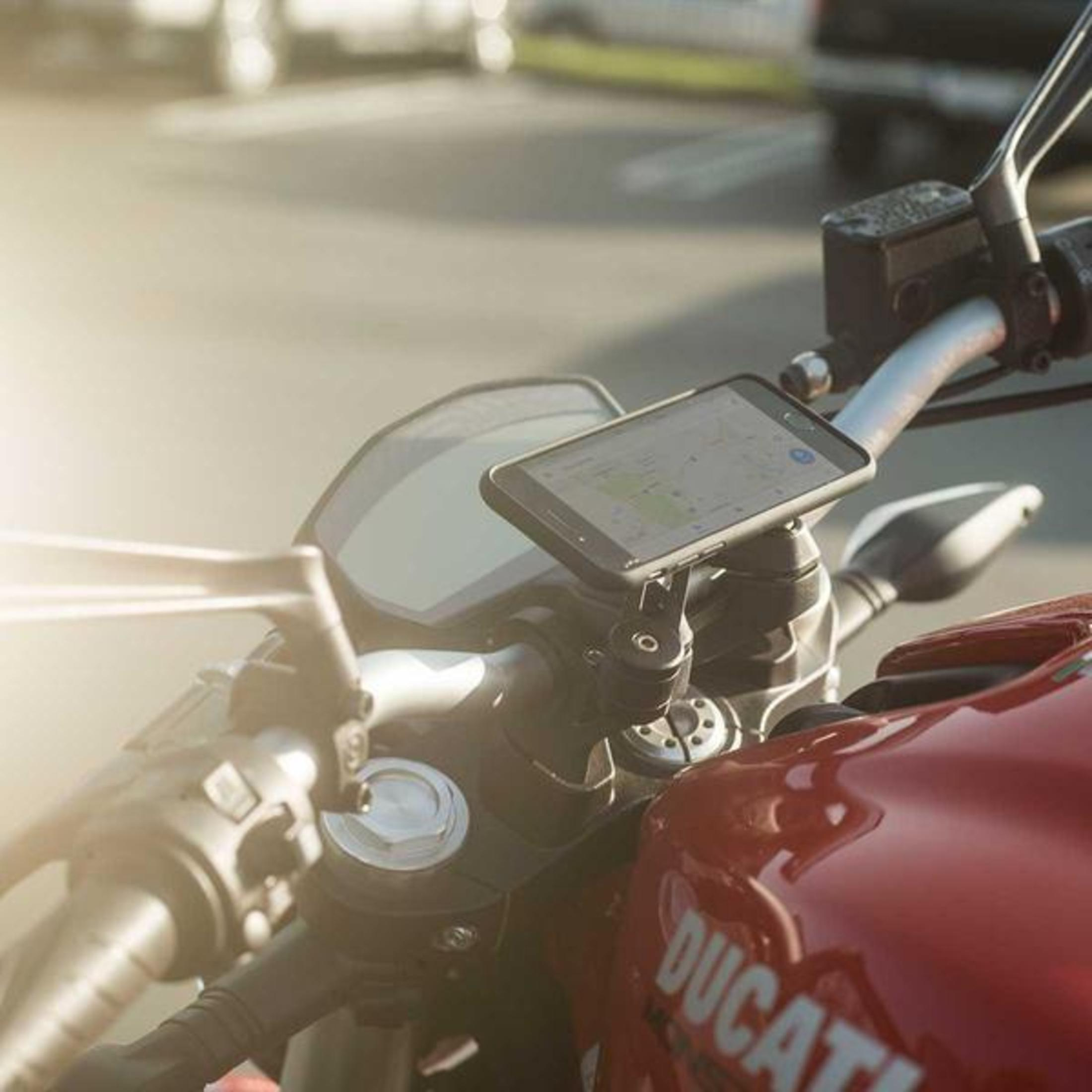 Ein Smartphone, das an einem Motorradlenker befestigt ist. Der Bildschirm zeigt eine Karte.