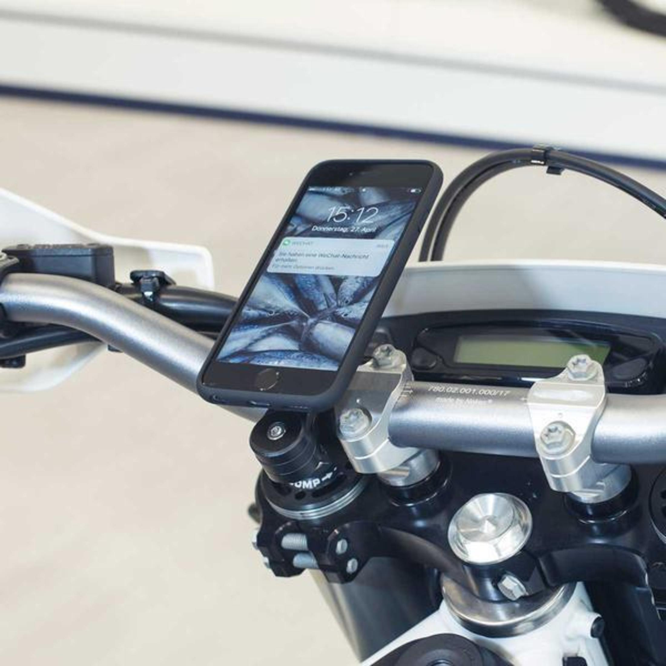 Smartphone auf Motorradlenker montiert, zeigt Uhrzeit und Fischbild, im Freien.