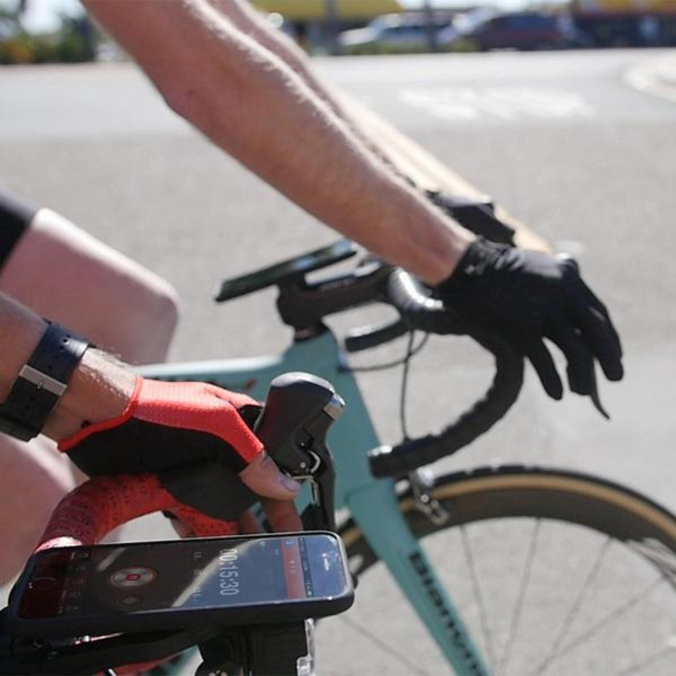 Hände eines Radfahrers mit Handschuhen am Fahrradlenker, Telefon am Lenker.
