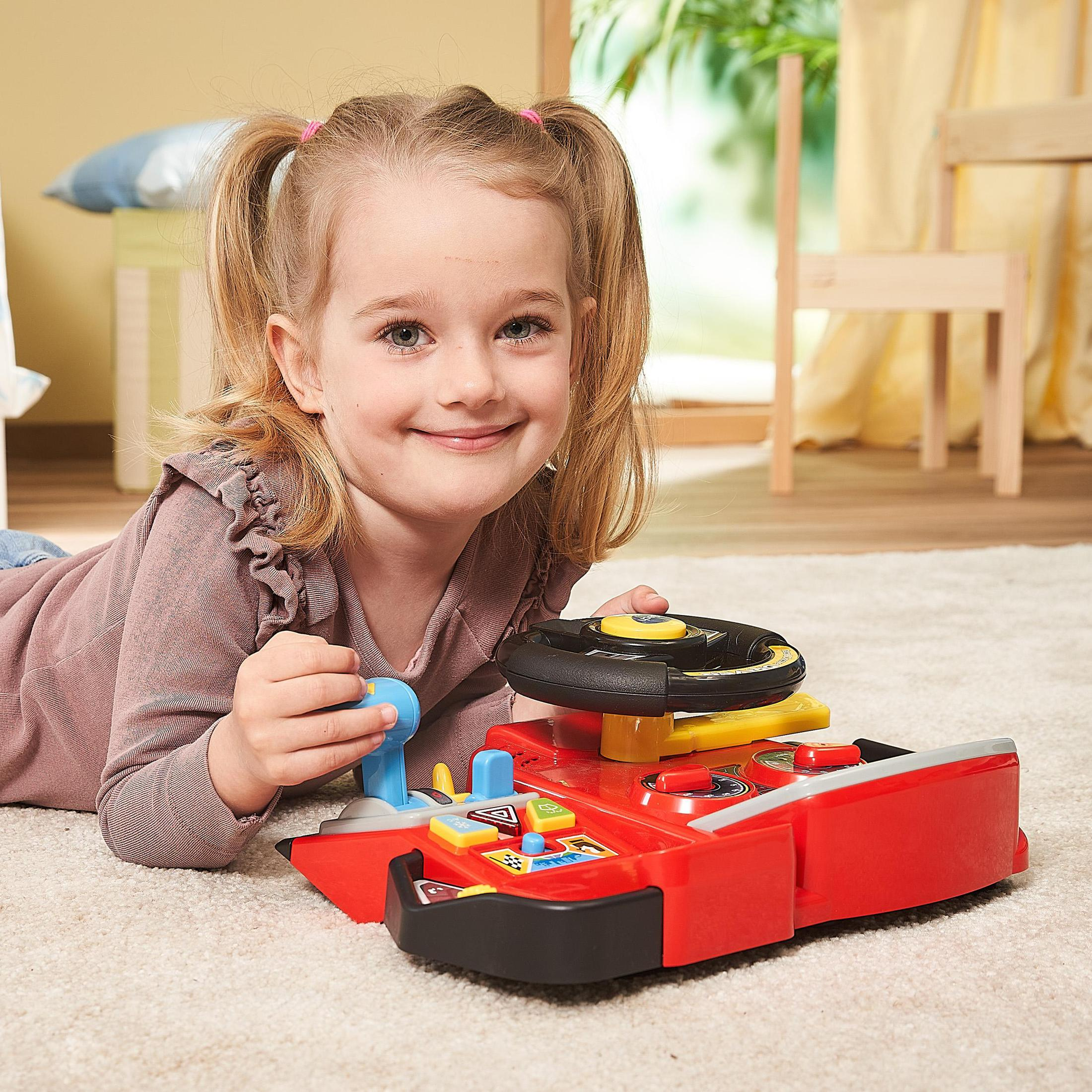 Une jeune fille est allongée sur un tapis blanc, souriante, jouant avec un volant jouet rouge.