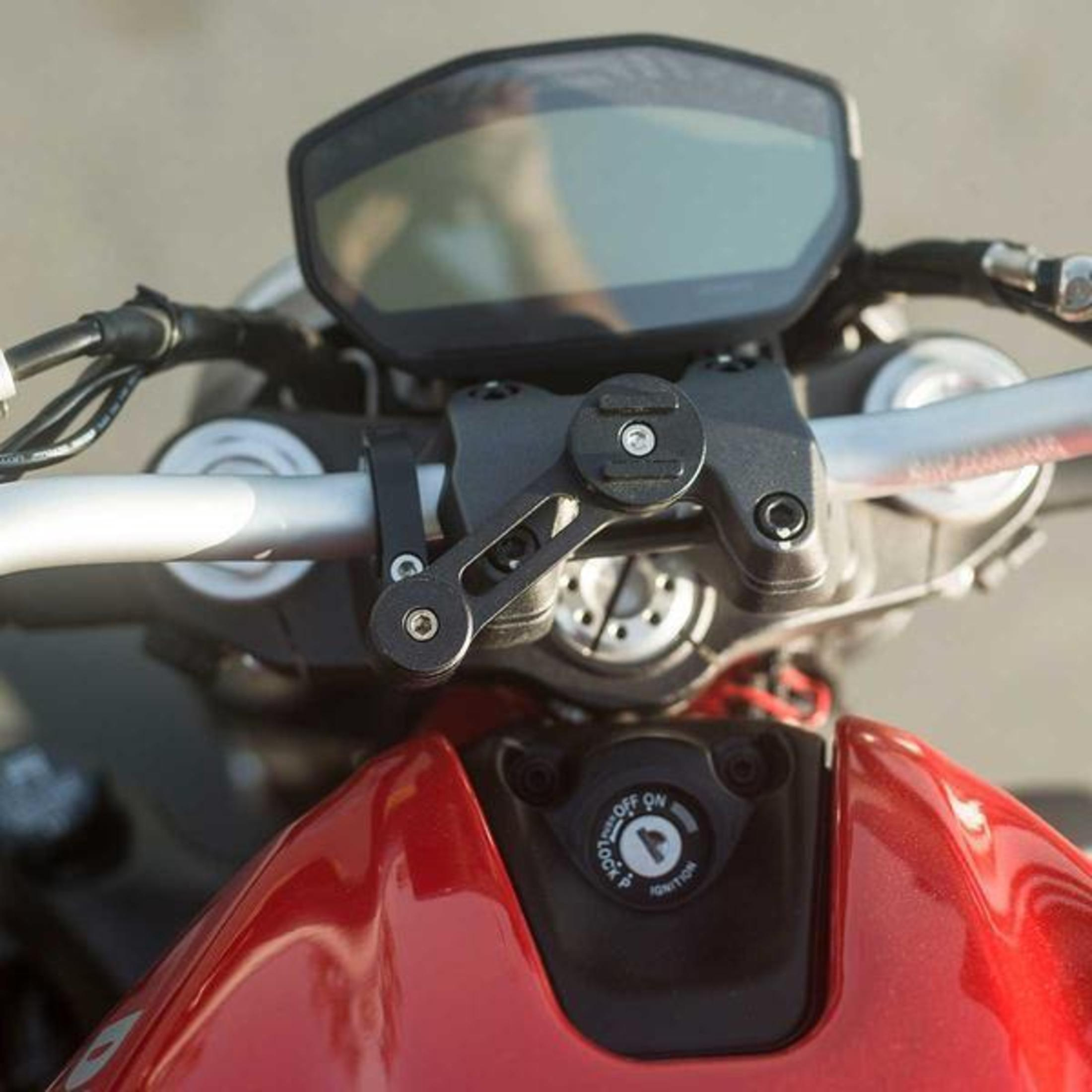 Motorradlenker mit Telefonhalterung und rotem Tank im Hintergrund.