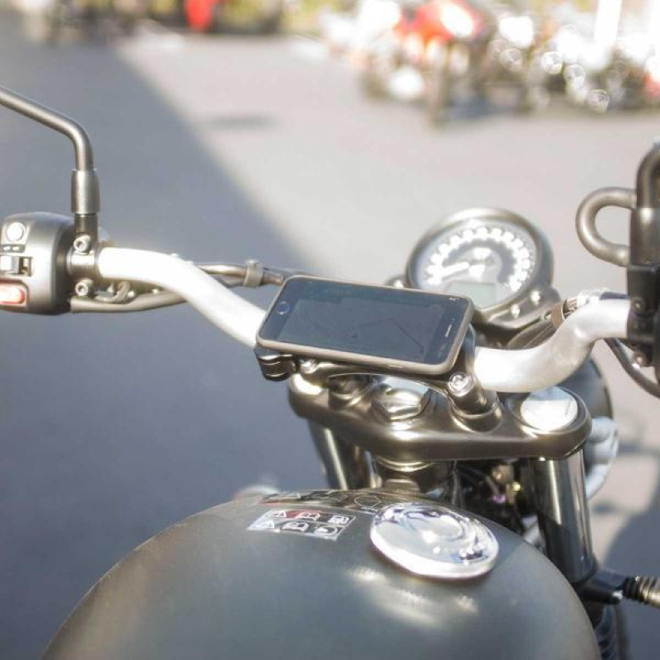 Motorradlenker mit einer Telefonhalterung, die ein Telefon hält. Das Motorrad steht auf einer Straße.