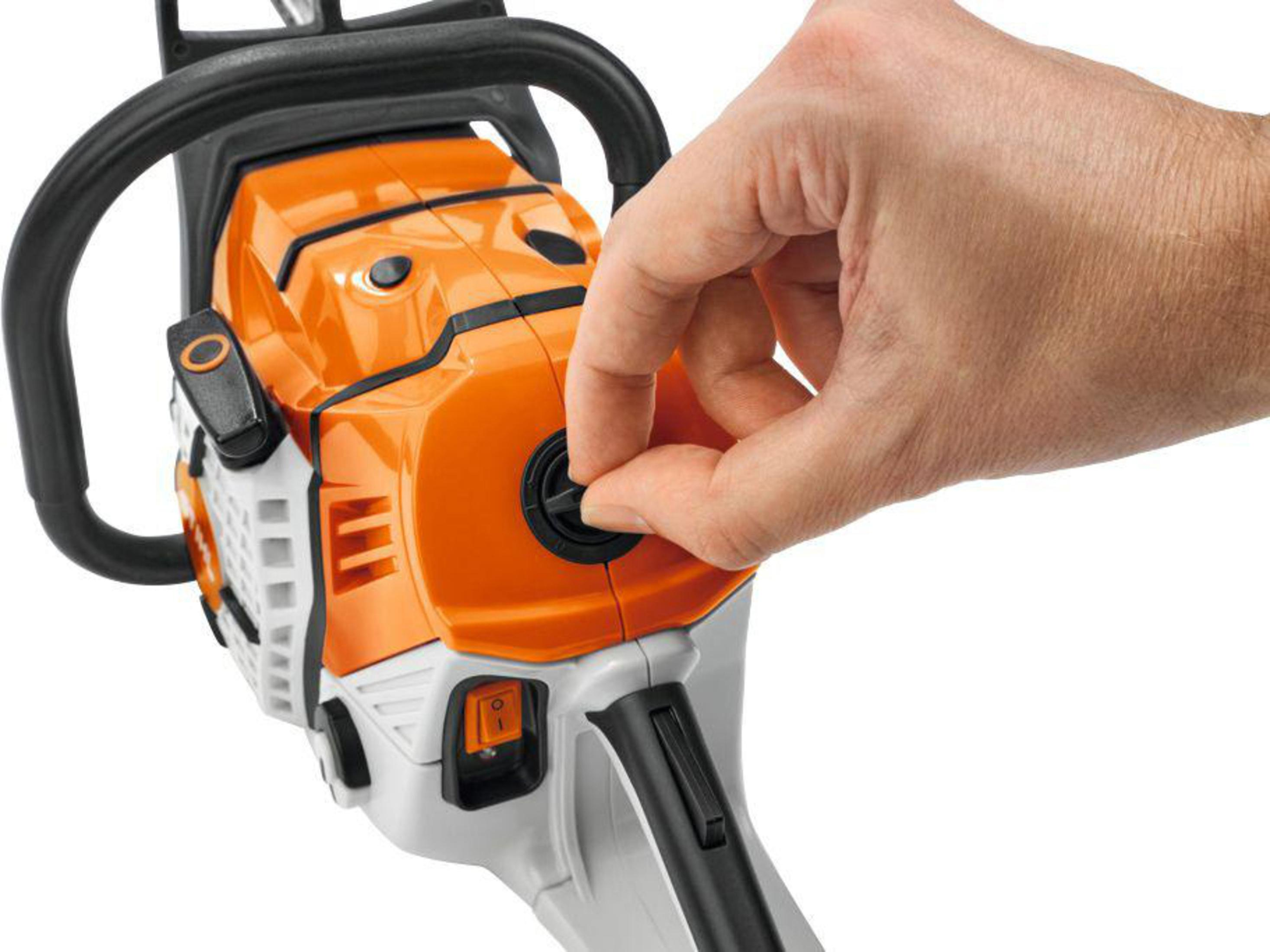 Hand stellt den Choke an einer orange-weißen Kettensäge mit schwarzen Griffen ein.