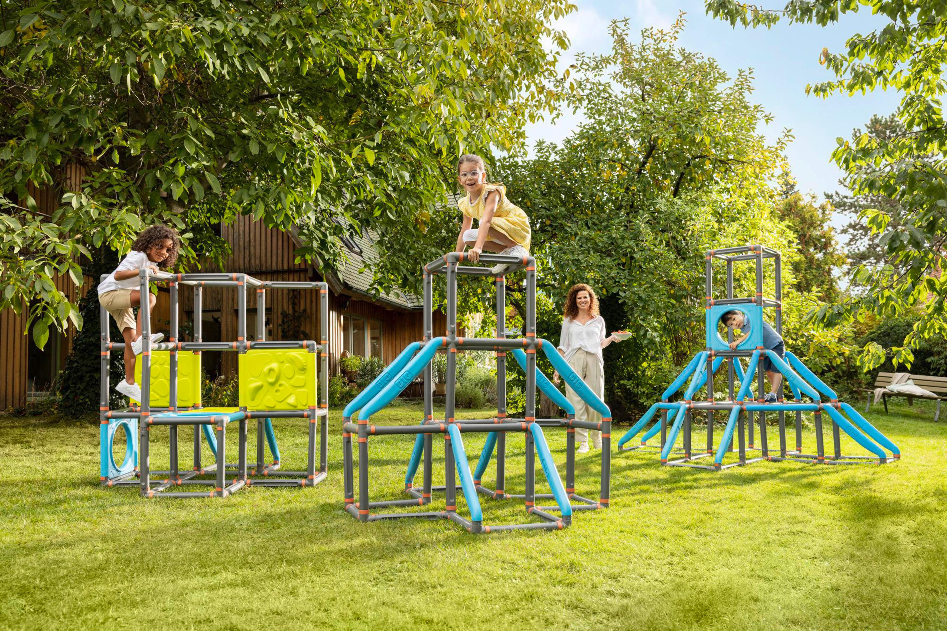 Kinder spielen auf einer Kletterstruktur im Freien, mit einem Erwachsenen in der Nähe.