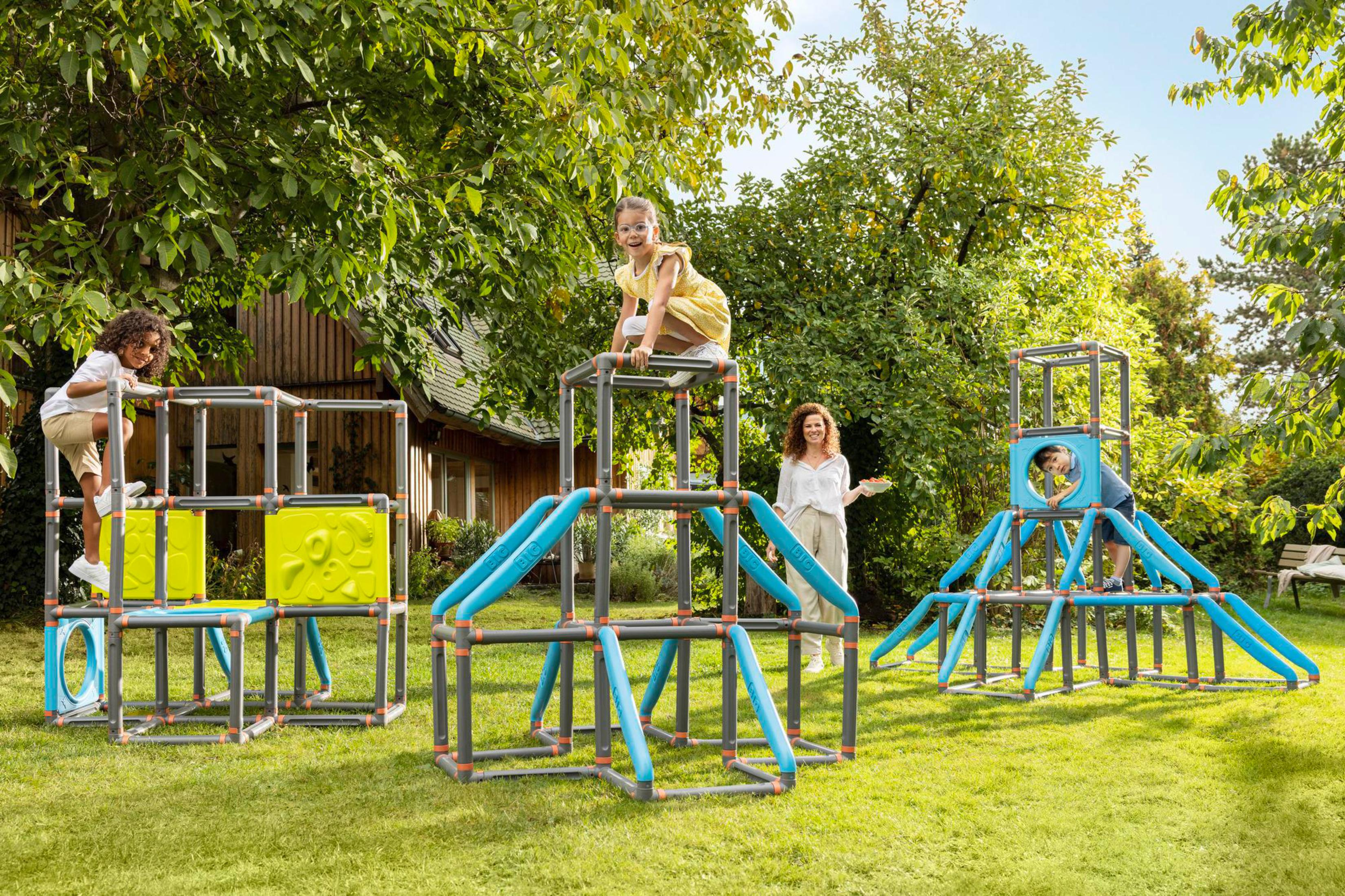 Kinder spielen auf einer bunten Kletterstruktur in einem sonnigen Garten.