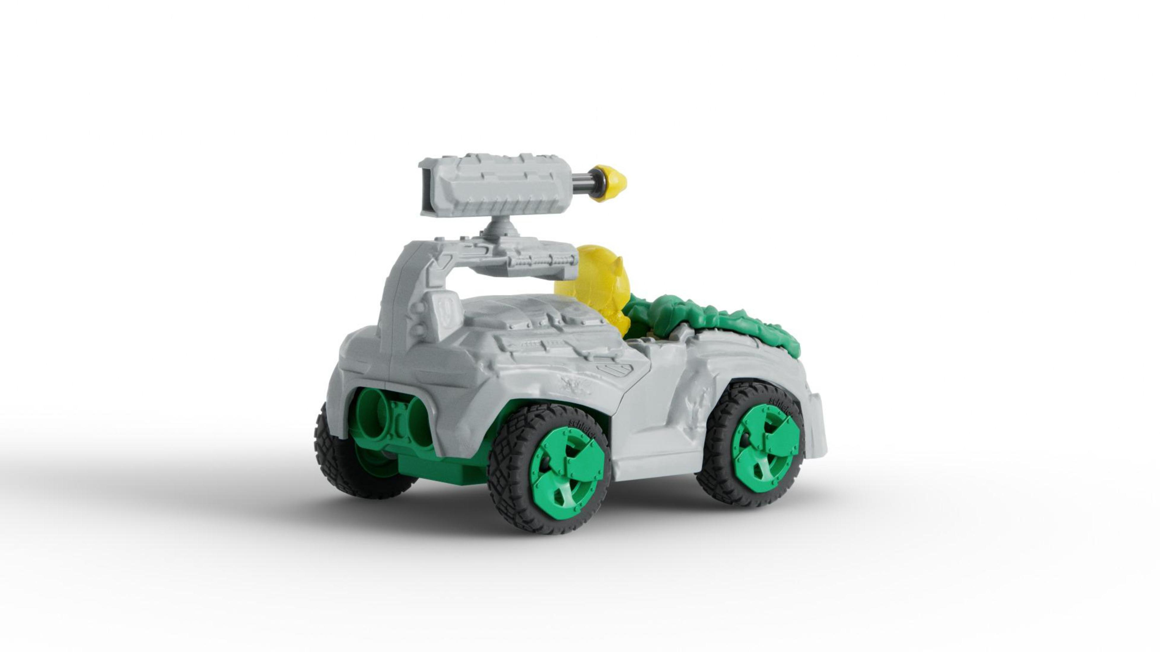 Szary pojazd zabawkowy z działem na górze i zielonymi kołami. Białe tło.