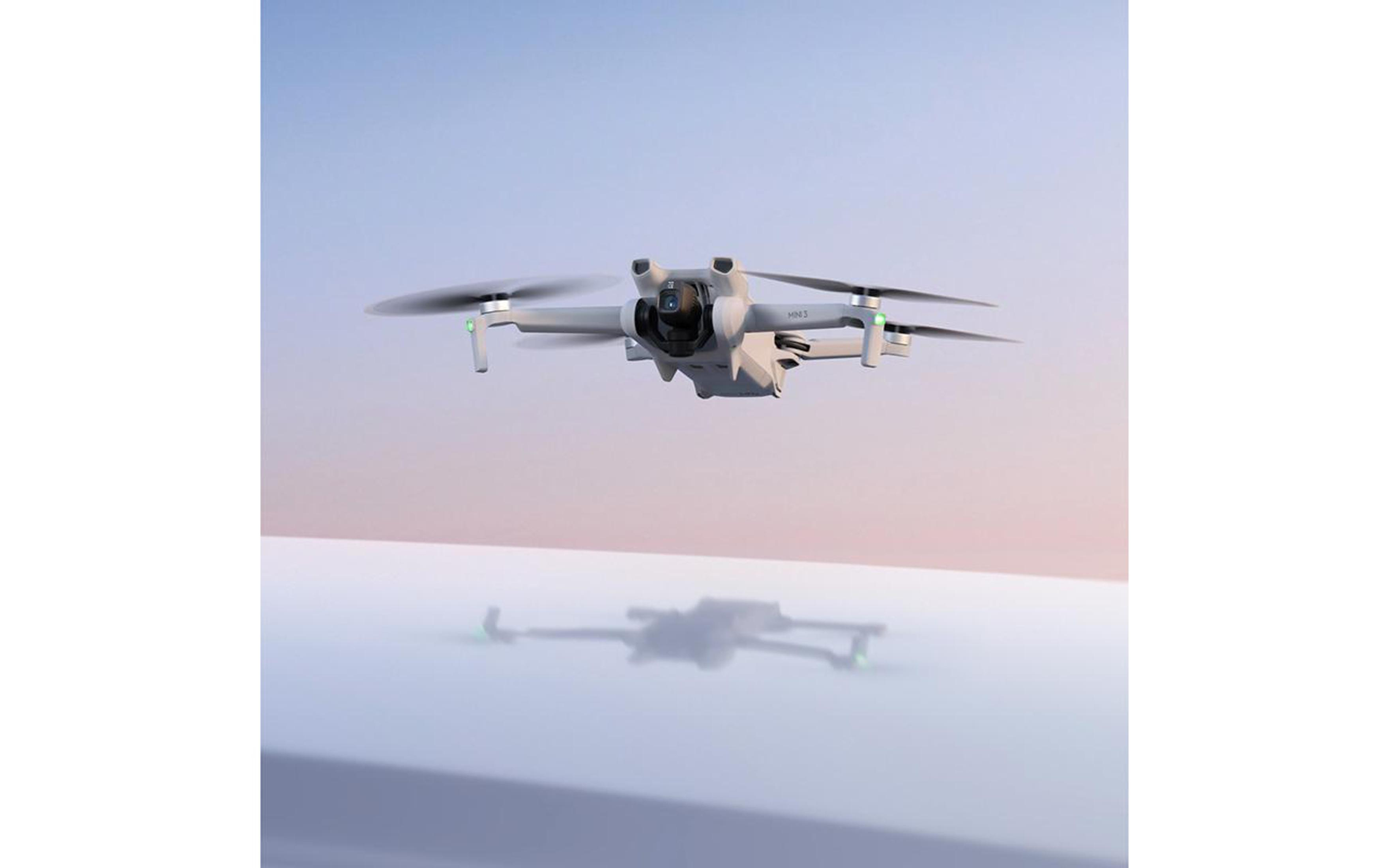 Un dron blanco volando en el cielo. Su reflejo se ve en el agua de abajo.