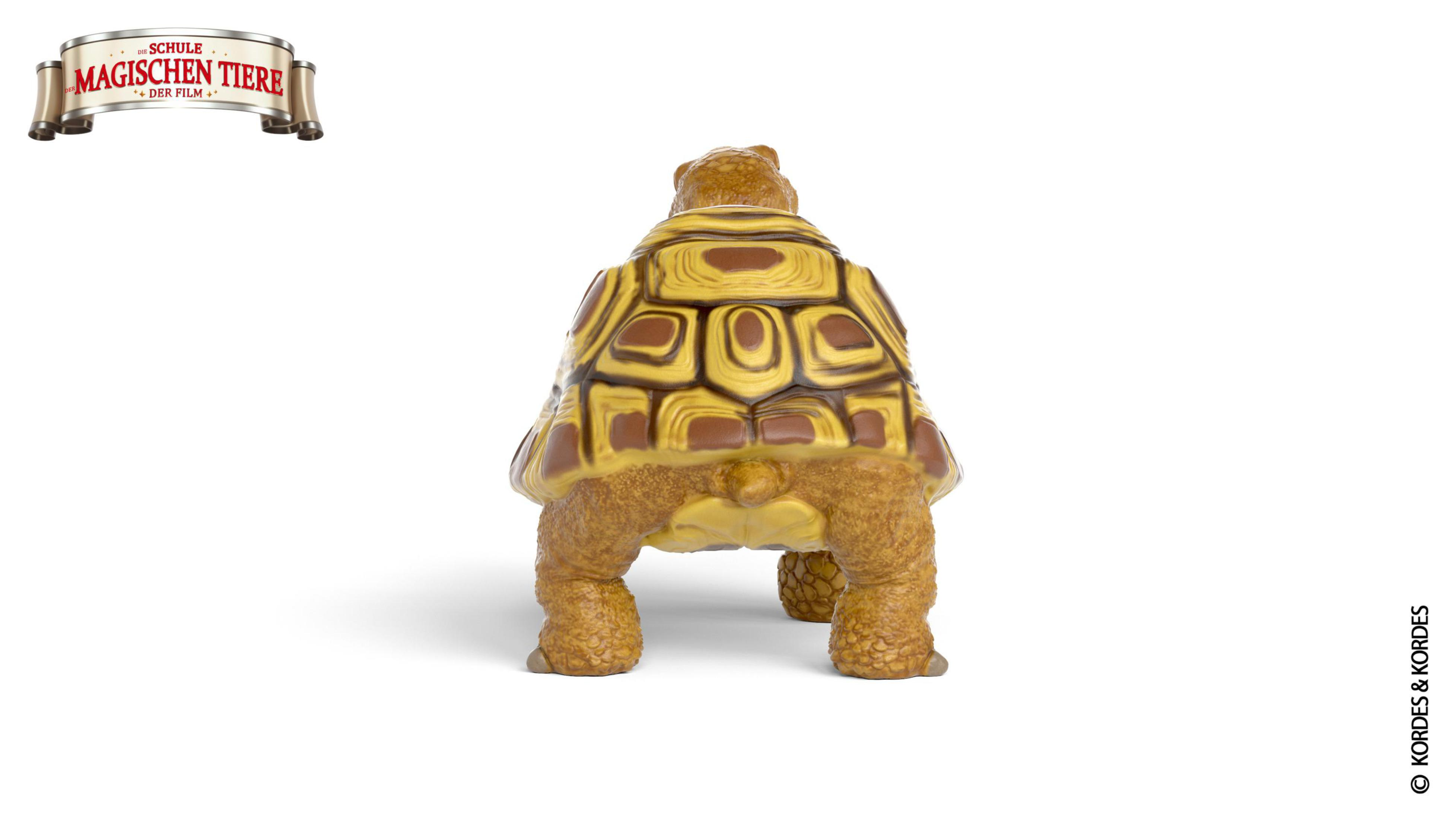 Tył zabawki żółwia z żółto-brązowym pancerzem, na białym tle.