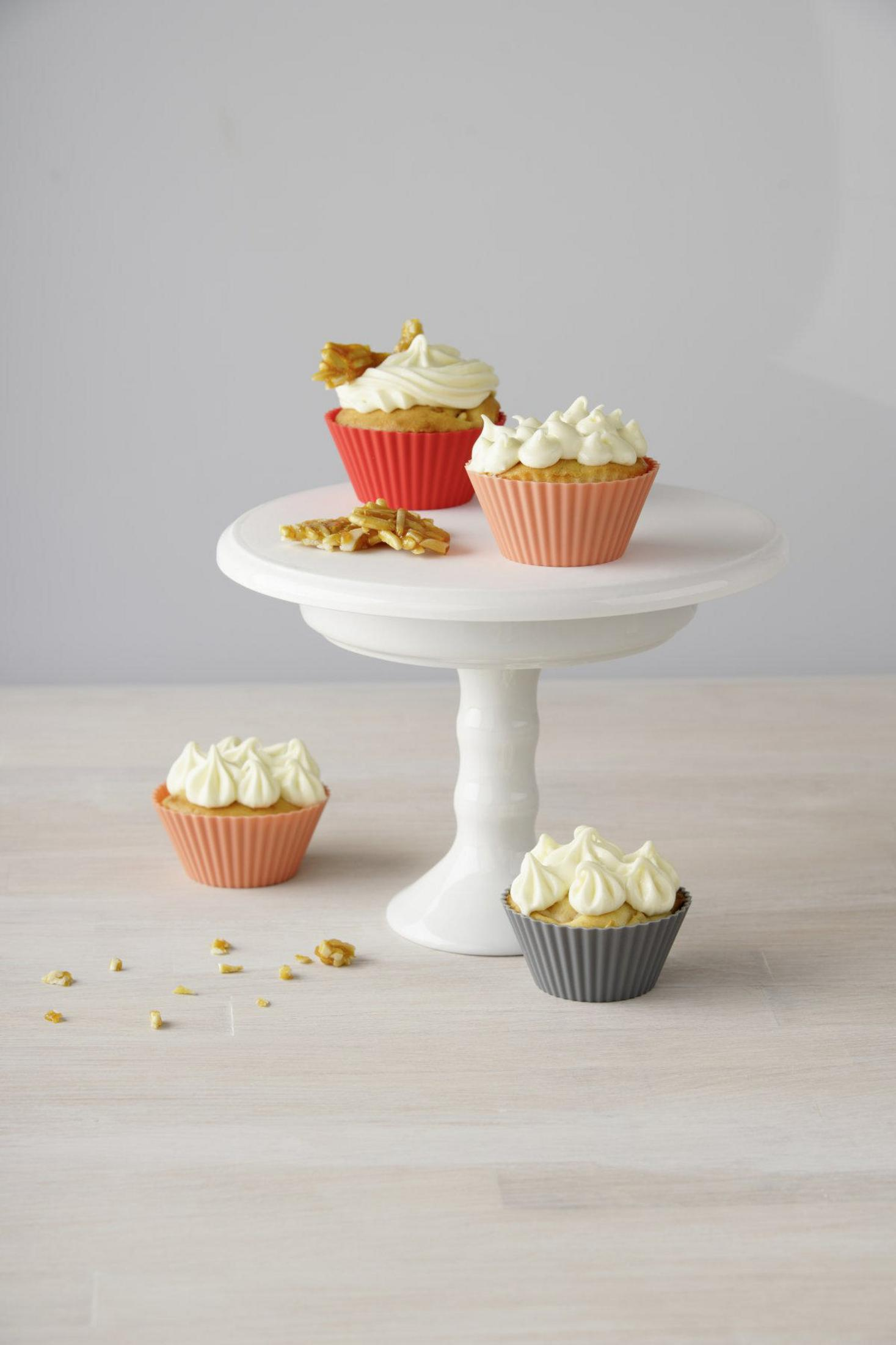 Cupcakes auf einem weißen Ständer. Drei Cupcakes stehen auf dem Ständer, einer am Boden.