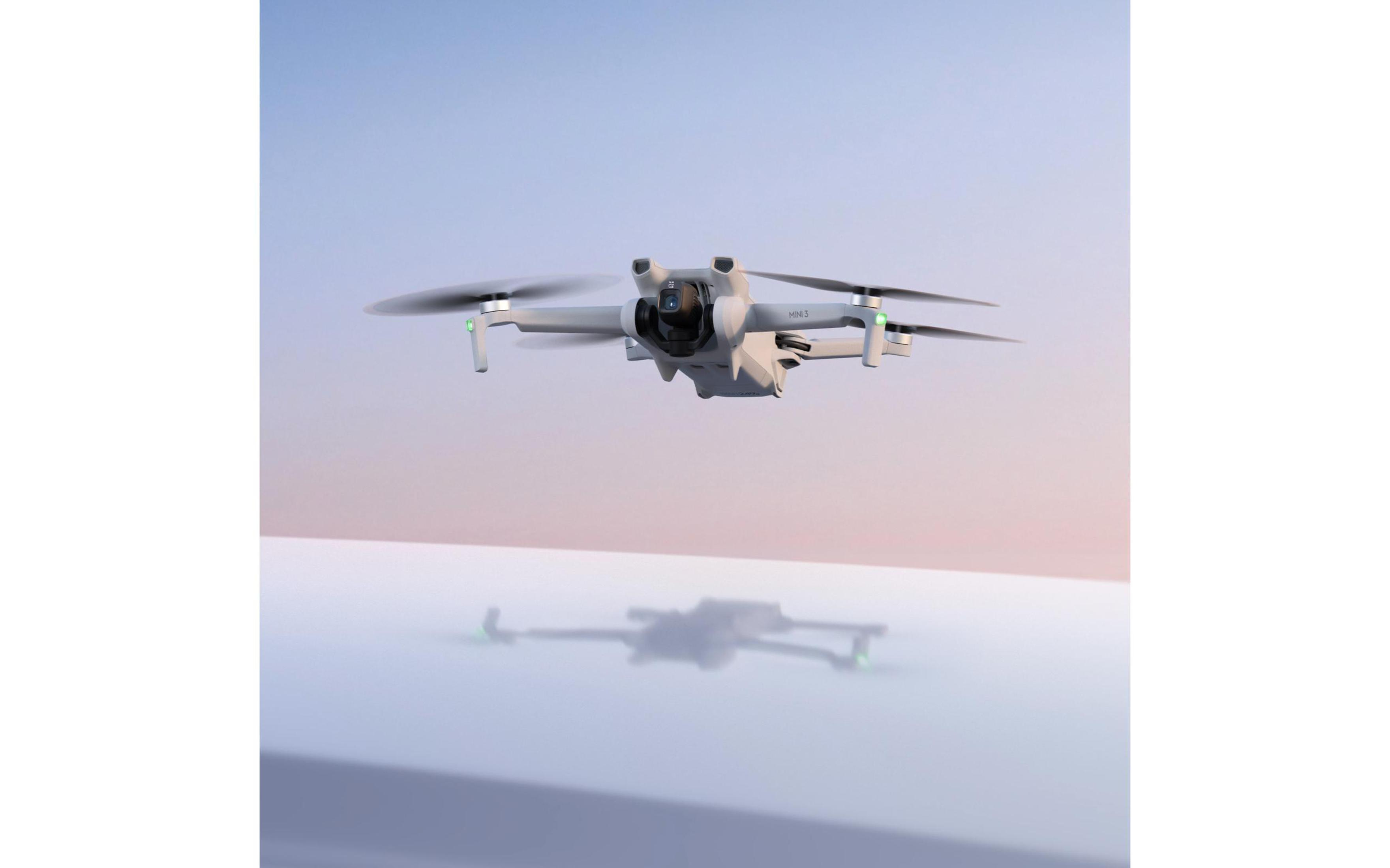 Un dron blanco con hélices giratorias está en el aire, con su reflejo visible debajo.