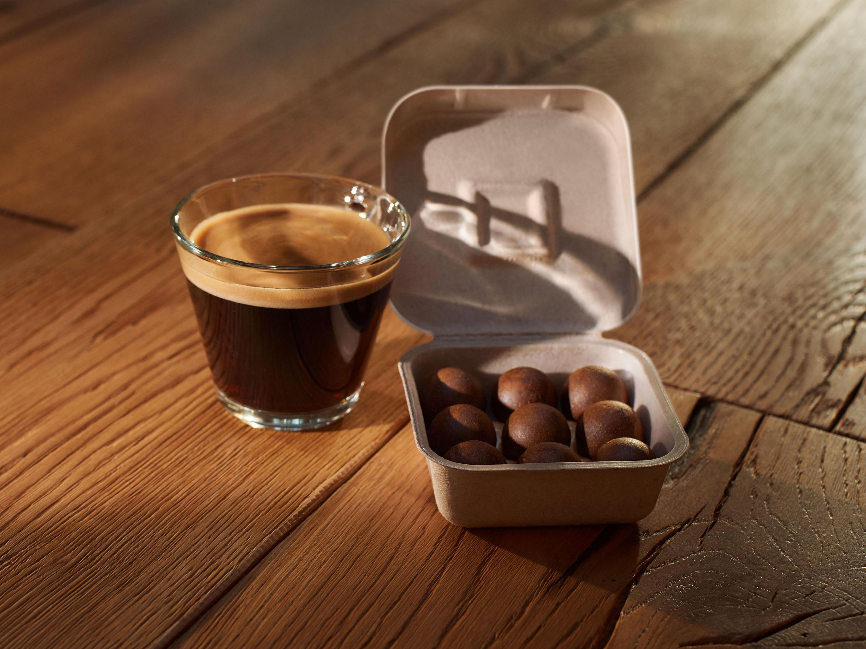 Una tazza di caffè e una scatola di cioccolatini su un tavolo di legno.