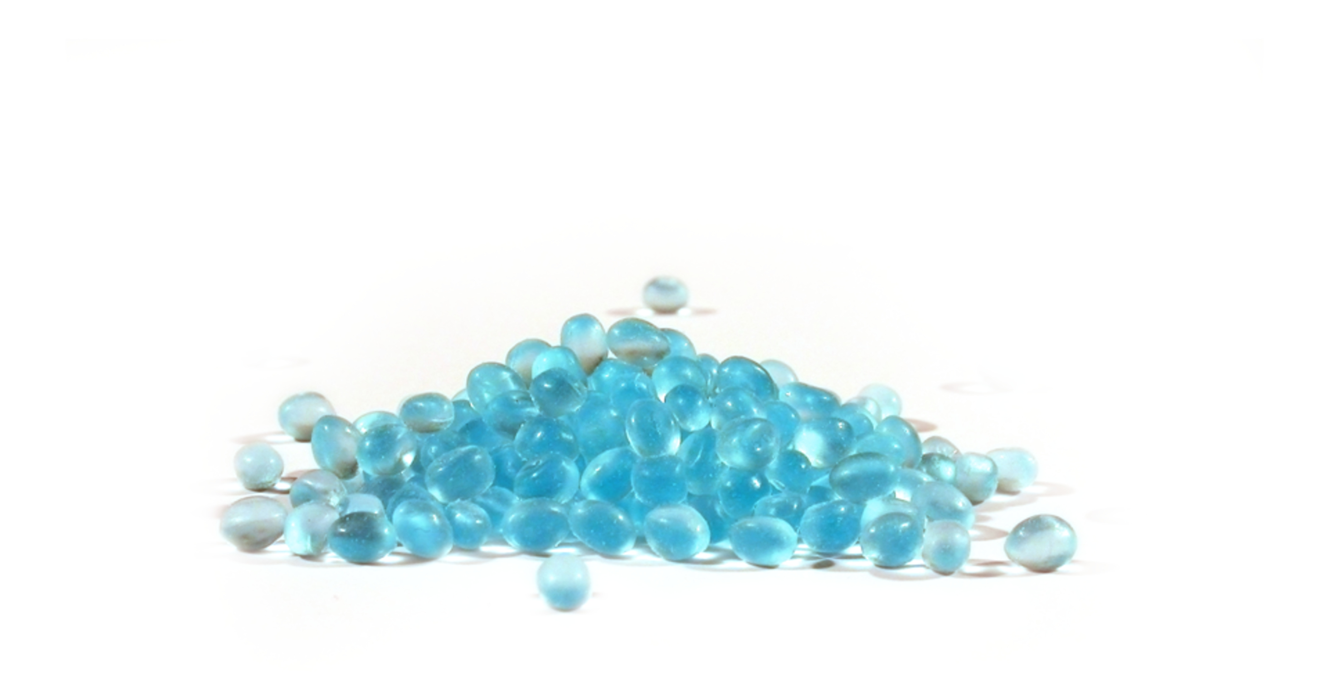 Ein Haufen durchscheinender blauer Gelperlen auf weißem Hintergrund. Die Perlen sind klein und kugelförmig.