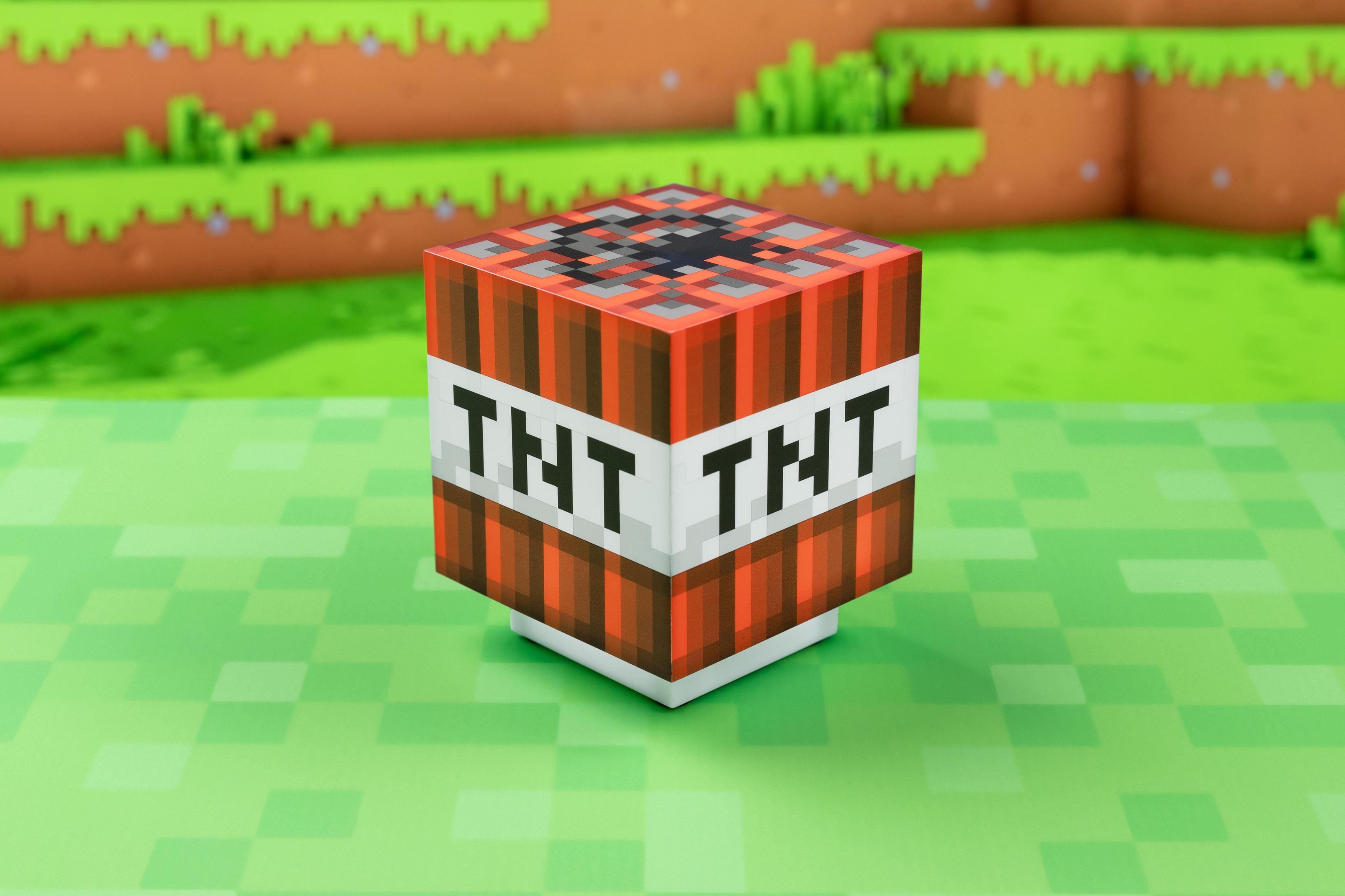 Blok TNT z Minecraft na tle zielonej trawy. Ma na sobie tekst TNT.