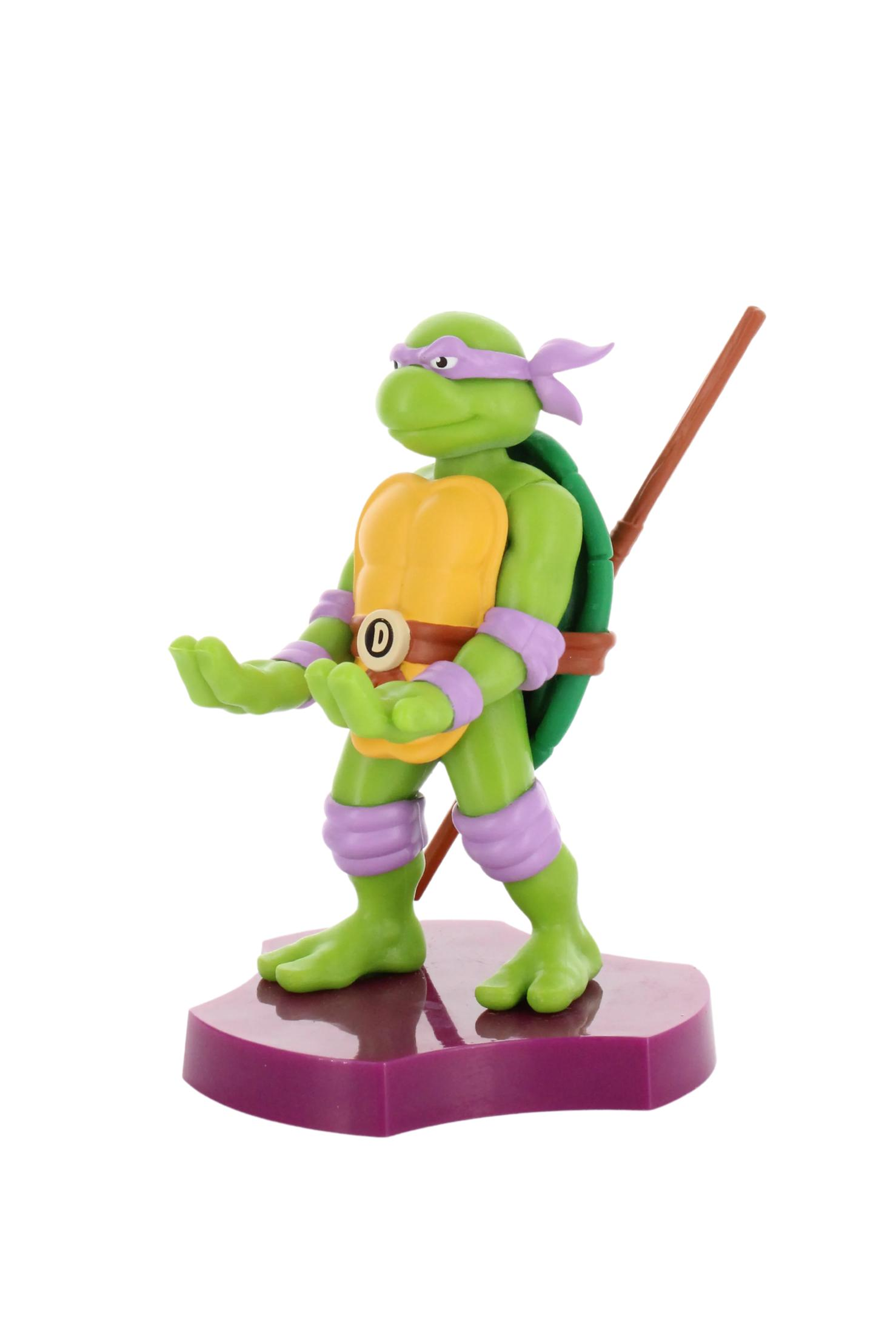 Figurka Donatello z Wojowniczych Żółwi Ninja. Fioletowa podstawa. Białe tło.