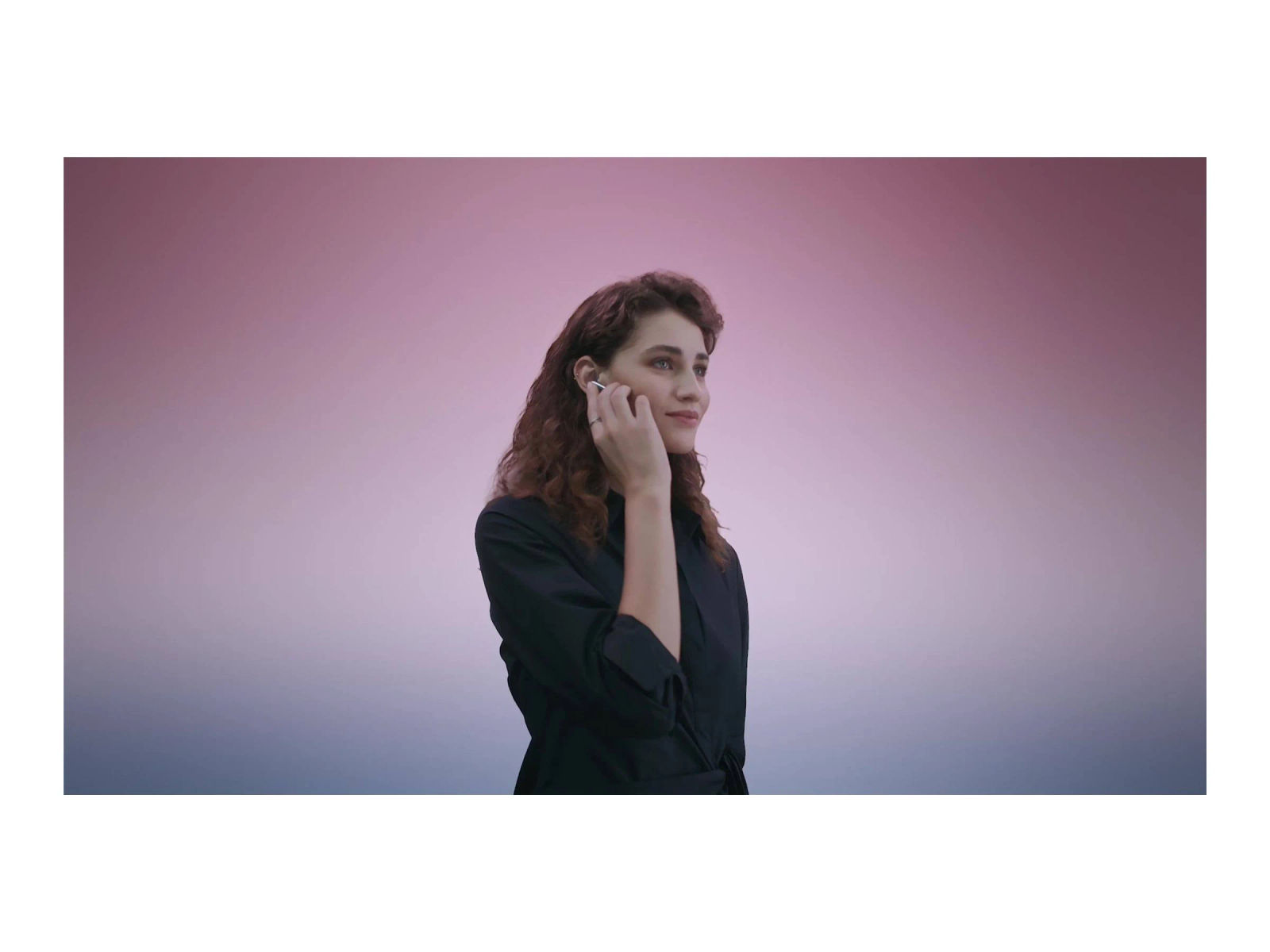 Kobieta z słuchawką, patrzy w lewo, na tle gradientu.