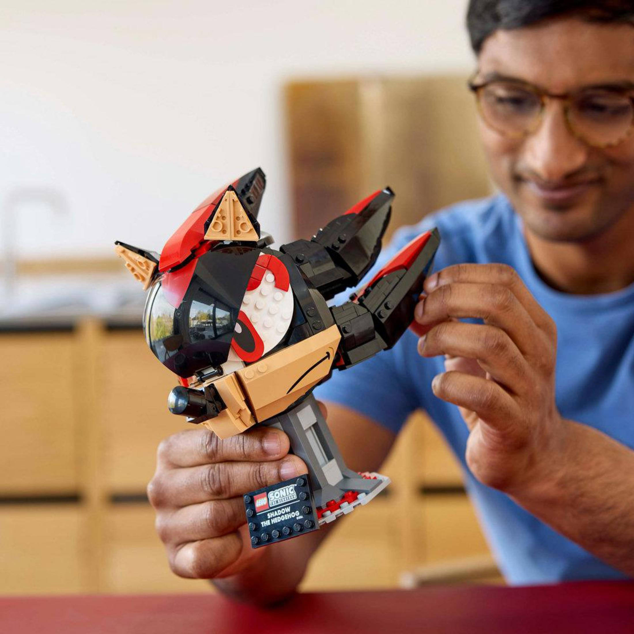 Bir adam Shadow the Hedgehog'un Lego modelini tutuyor. Model siyah ve kırmızı.