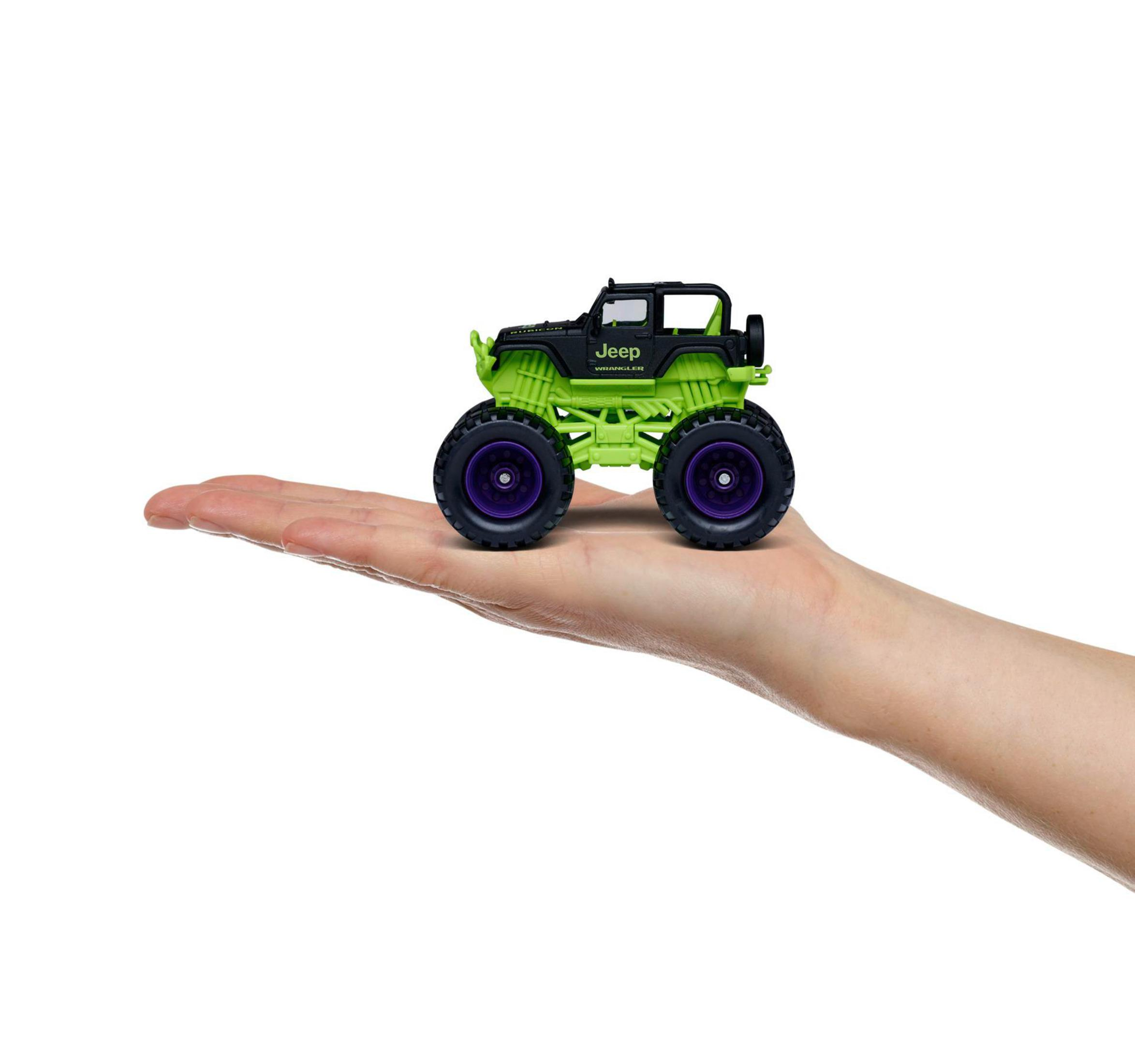 Zielono-czarny zabawkowy Jeep Wrangler na dłoni. Fioletowe koła i białe tło.