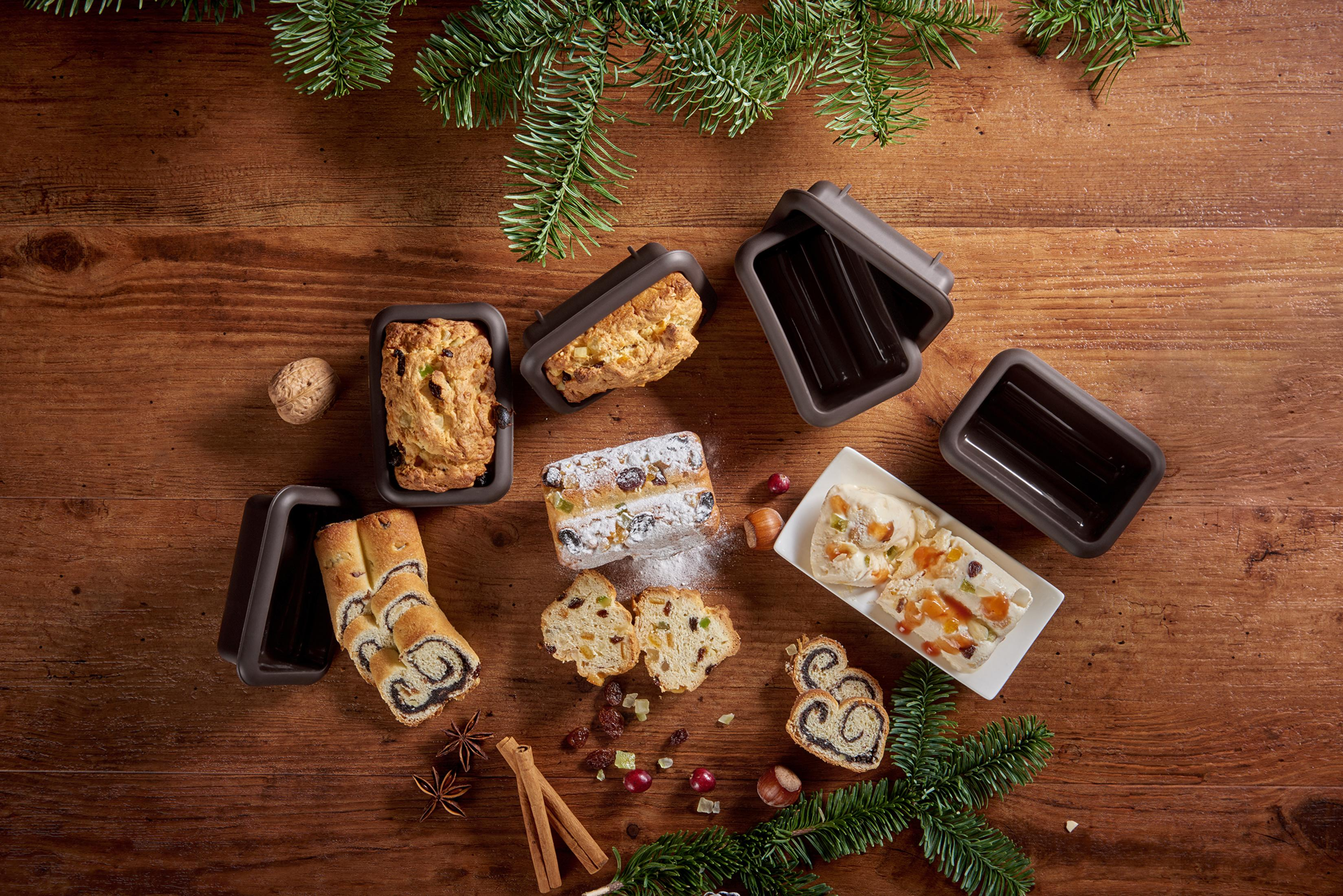 Świąteczne wypieki i formy do pieczenia na drewnianym stole z gałęziami iglastymi.